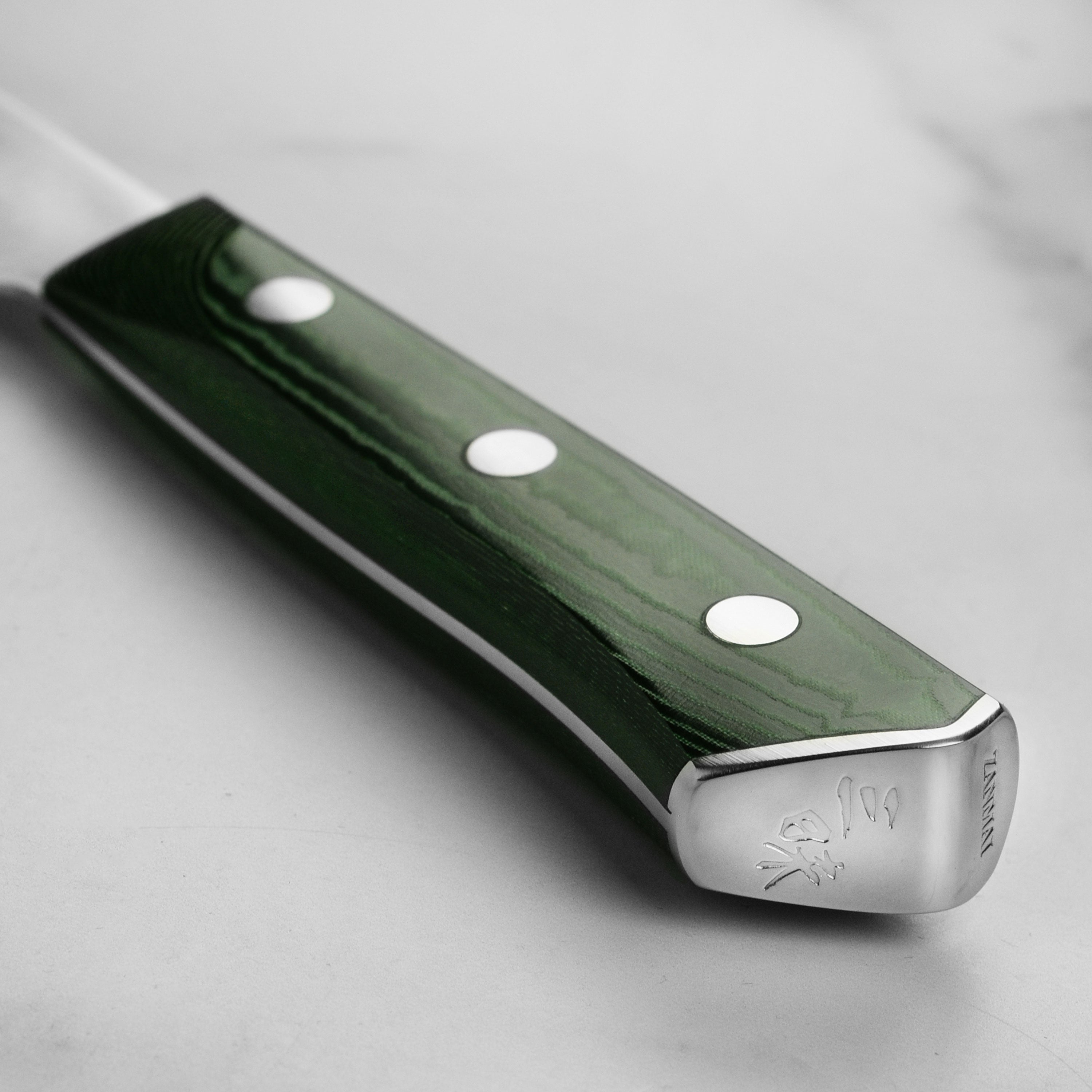 Ergonomic Green Micarta handle of the Zanmai Forest chef knife, highlighting its triple-rivet design.