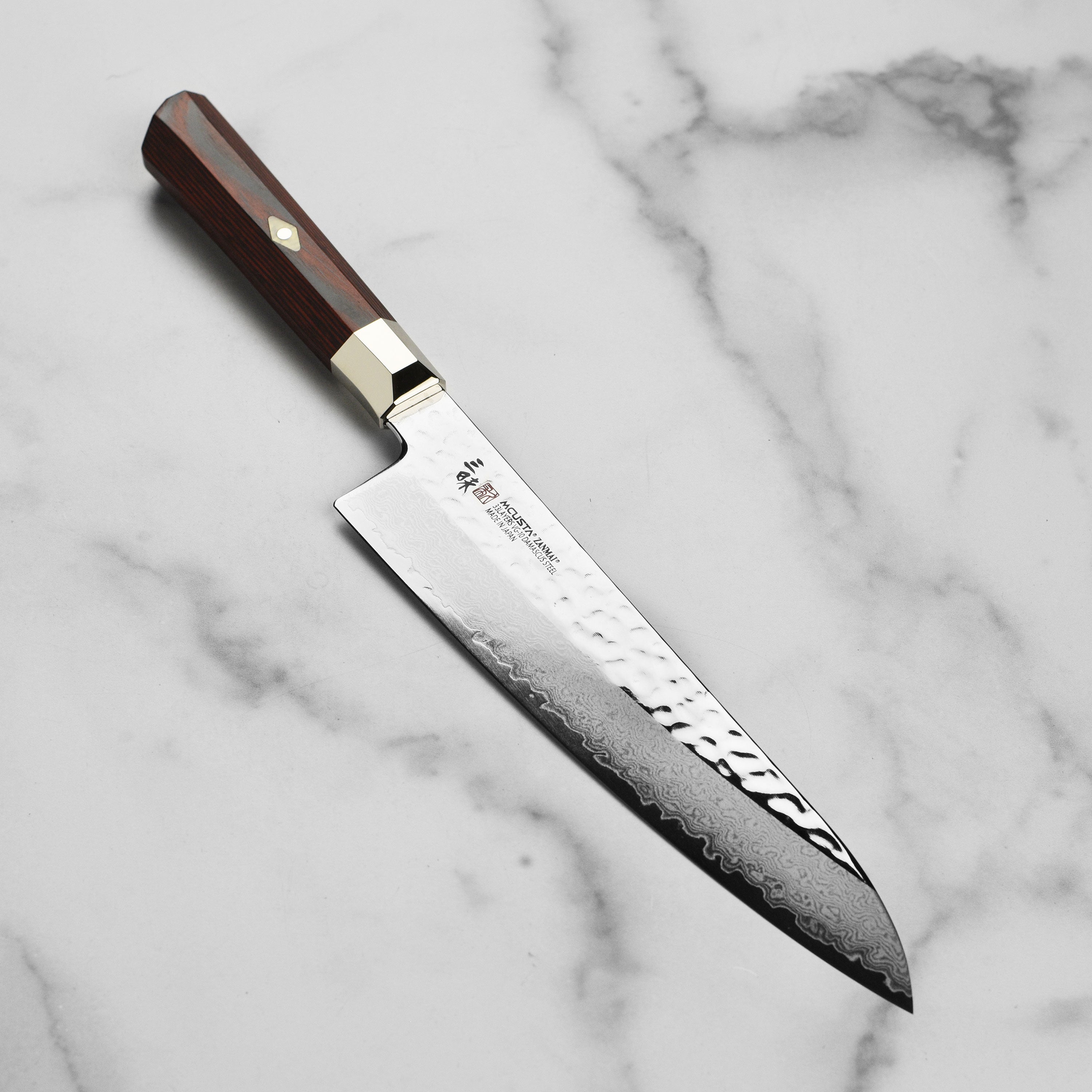 Front view of Zanmai Supreme Damascus Gyuto with hammered finish and Pakkawood handle