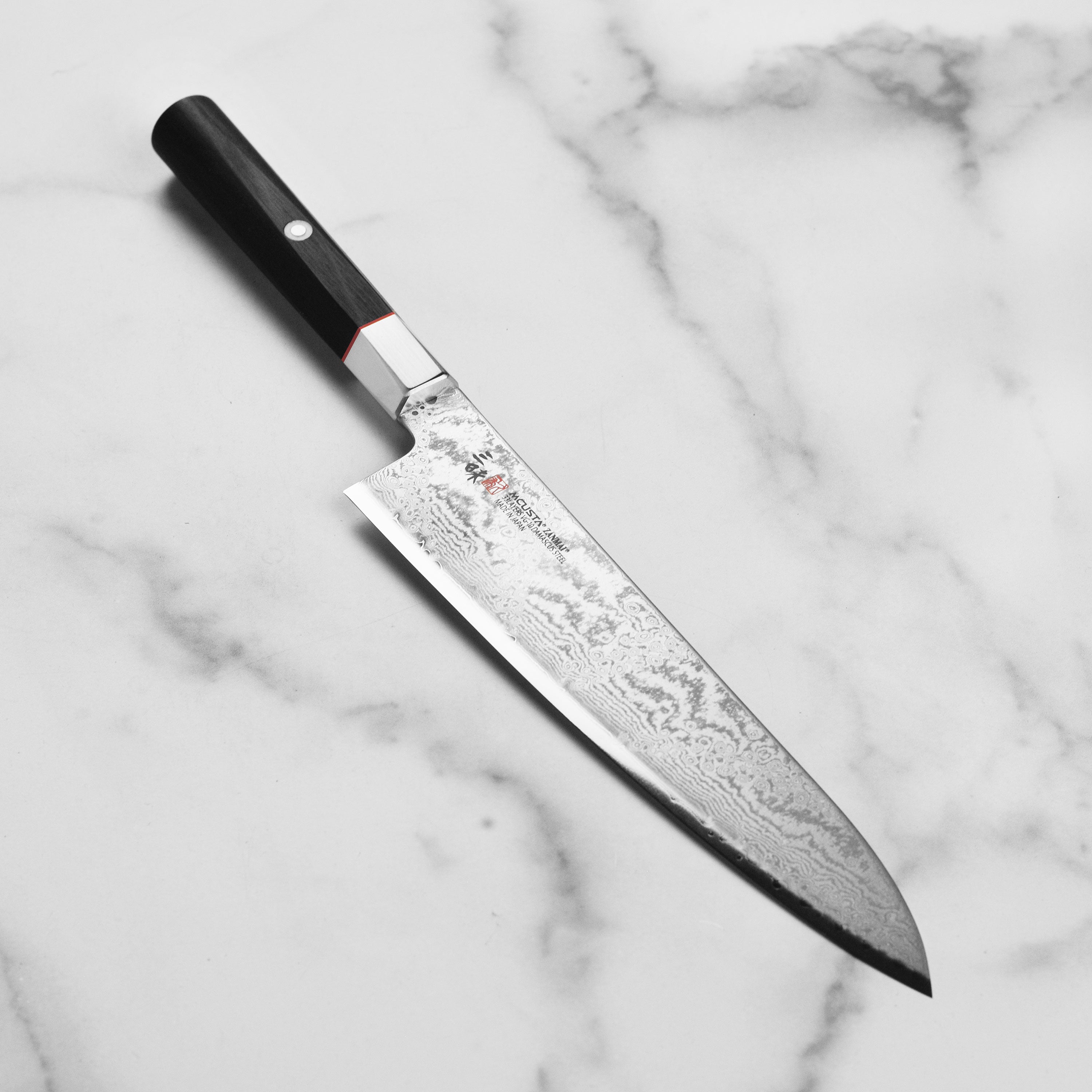 Zanmai Premier Damascus Gyuto Knife showing the polished VG10 Sanmai core and elegant Pakkawood handle.