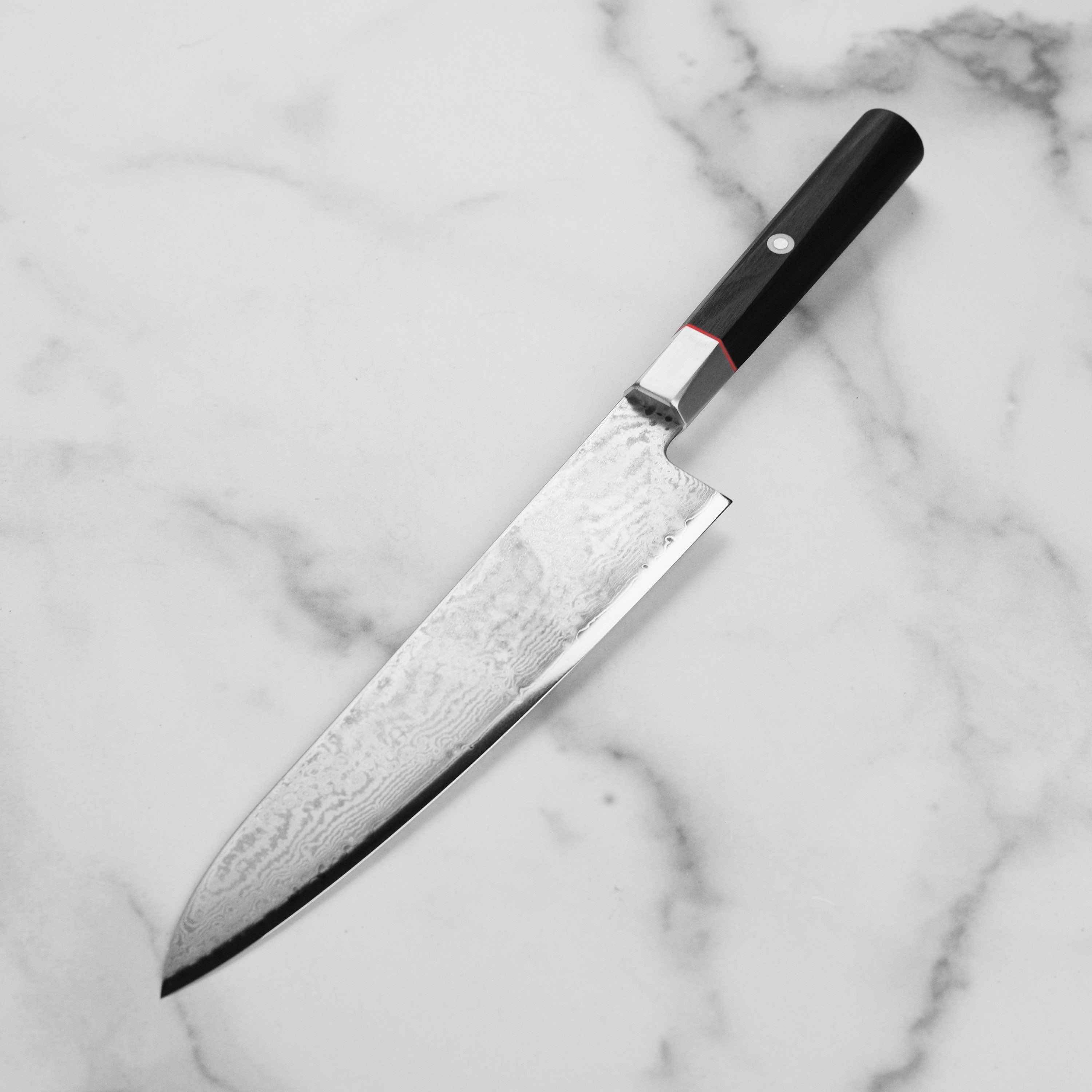 Close-up of the Zanmai Damascus knifes sharp edge and intricate 33-layer design.