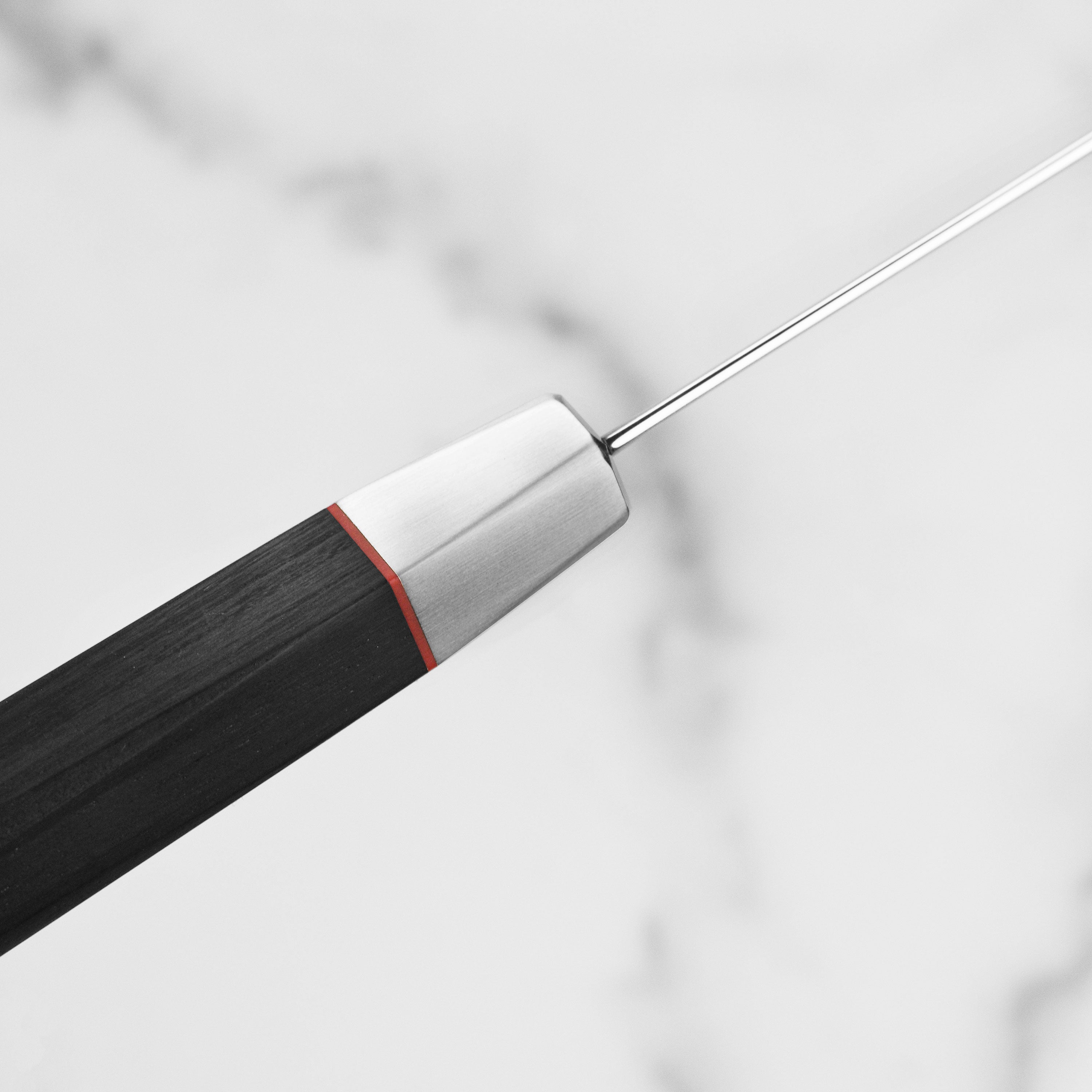 Detailed shot of the knifes handle featuring the red spacer and Japanese mosaic pin, demonstrating craftsmanship.