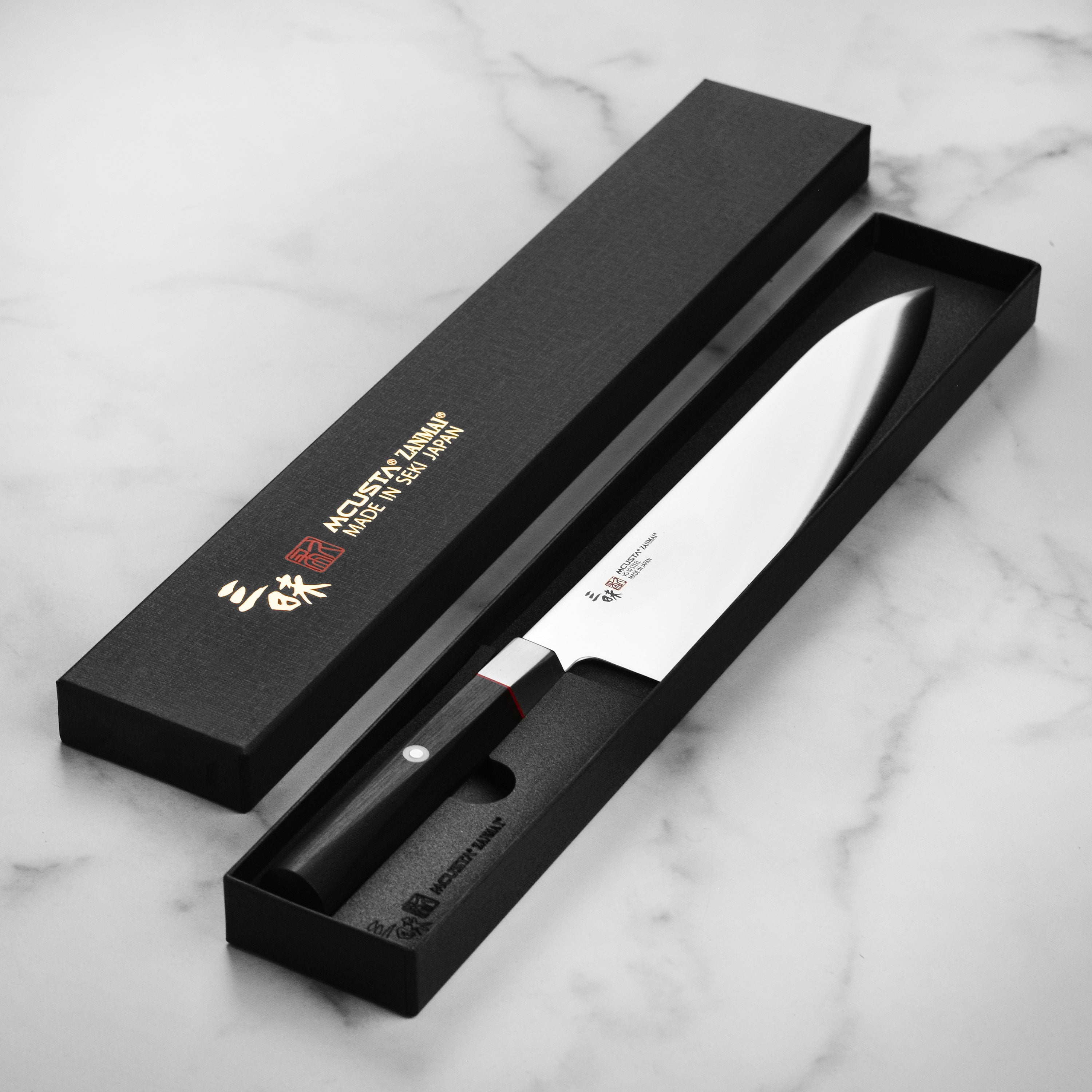 Detailed shot of the knifes handle featuring the red spacer and Japanese mosaic pin, demonstrating craftsmanship.