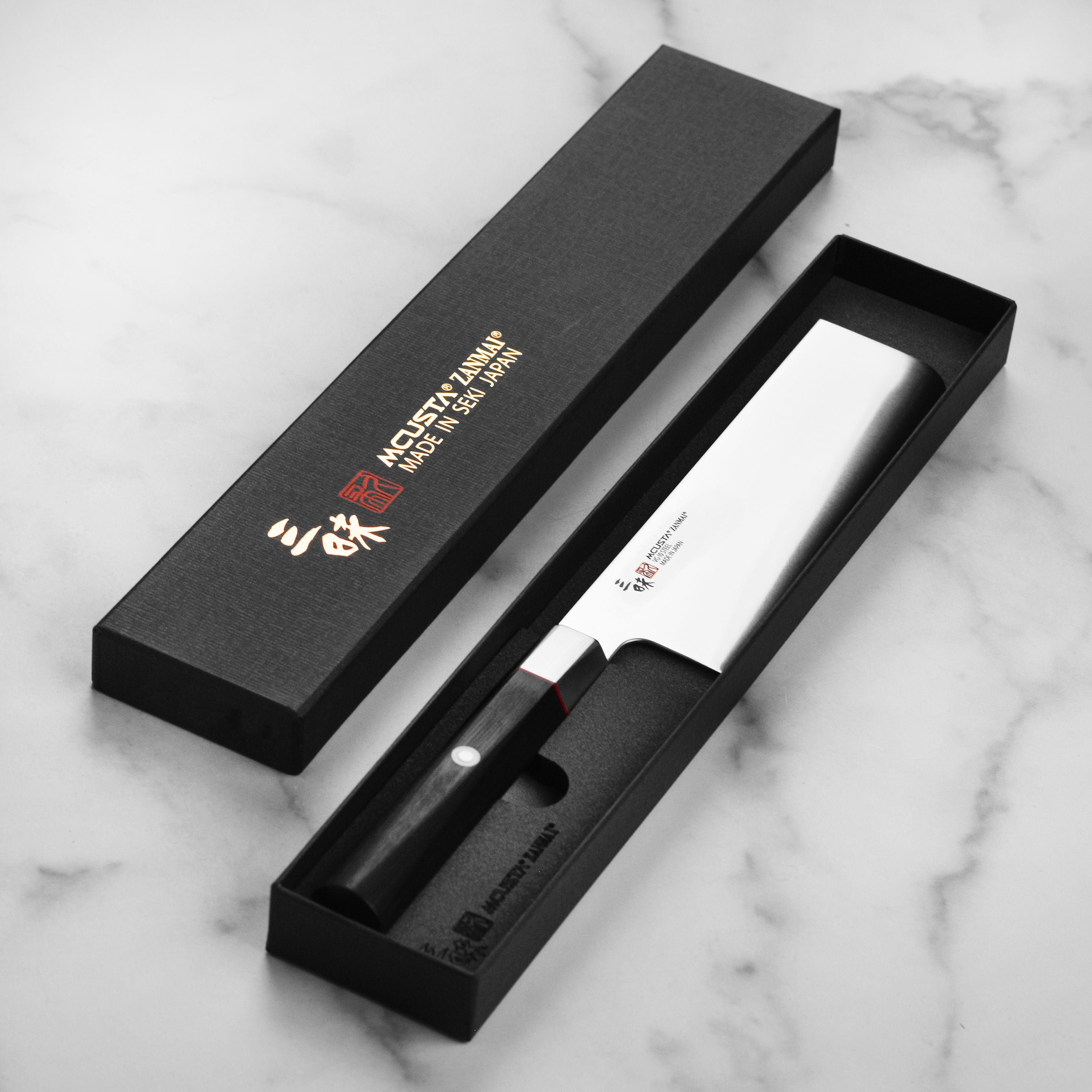 Zanmai Nakiri knife in action, effortlessly slicing fresh vegetables on a wooden cutting board.