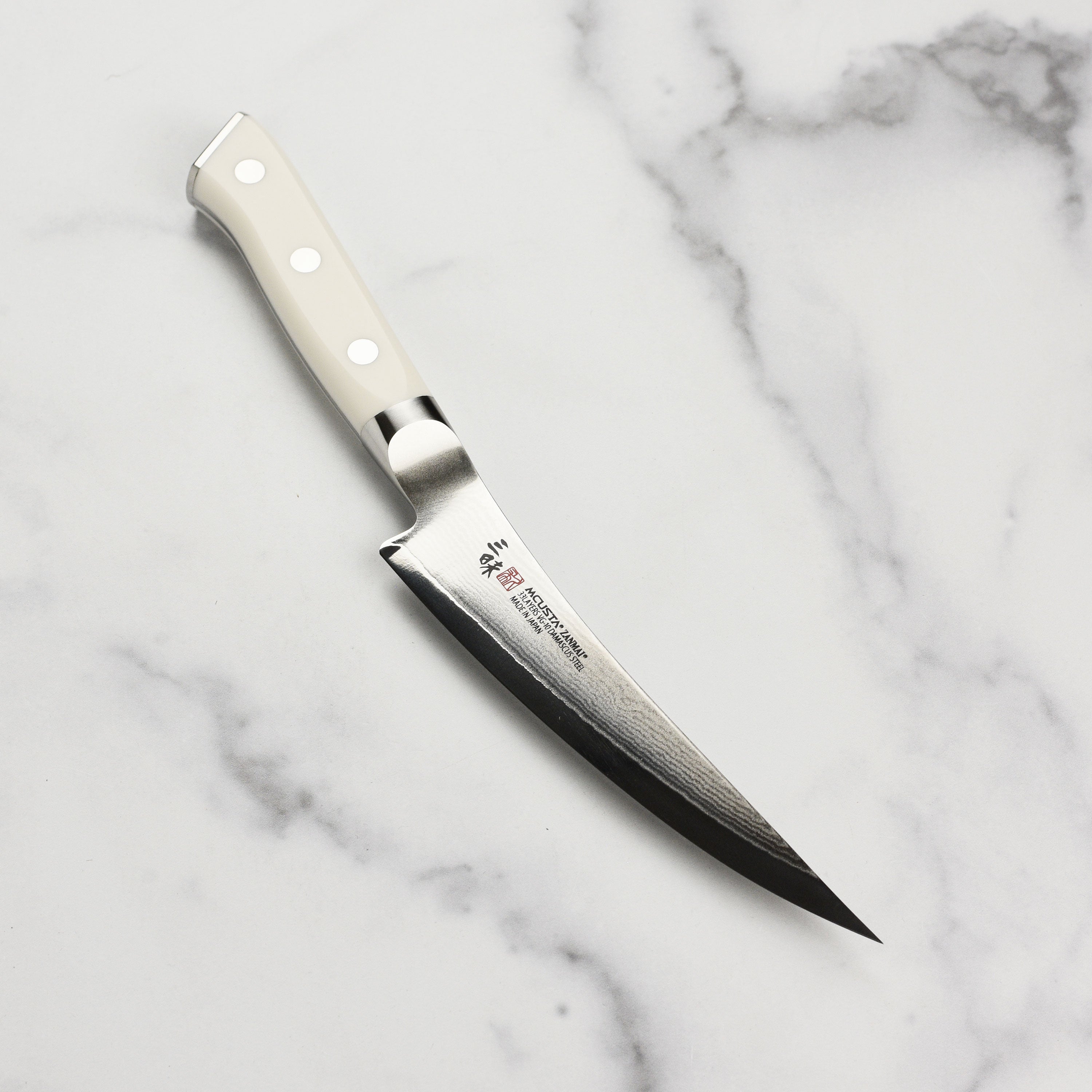 Close-up view of the Zanmai Damascus knife blade highlighting its 33-layer construction.
