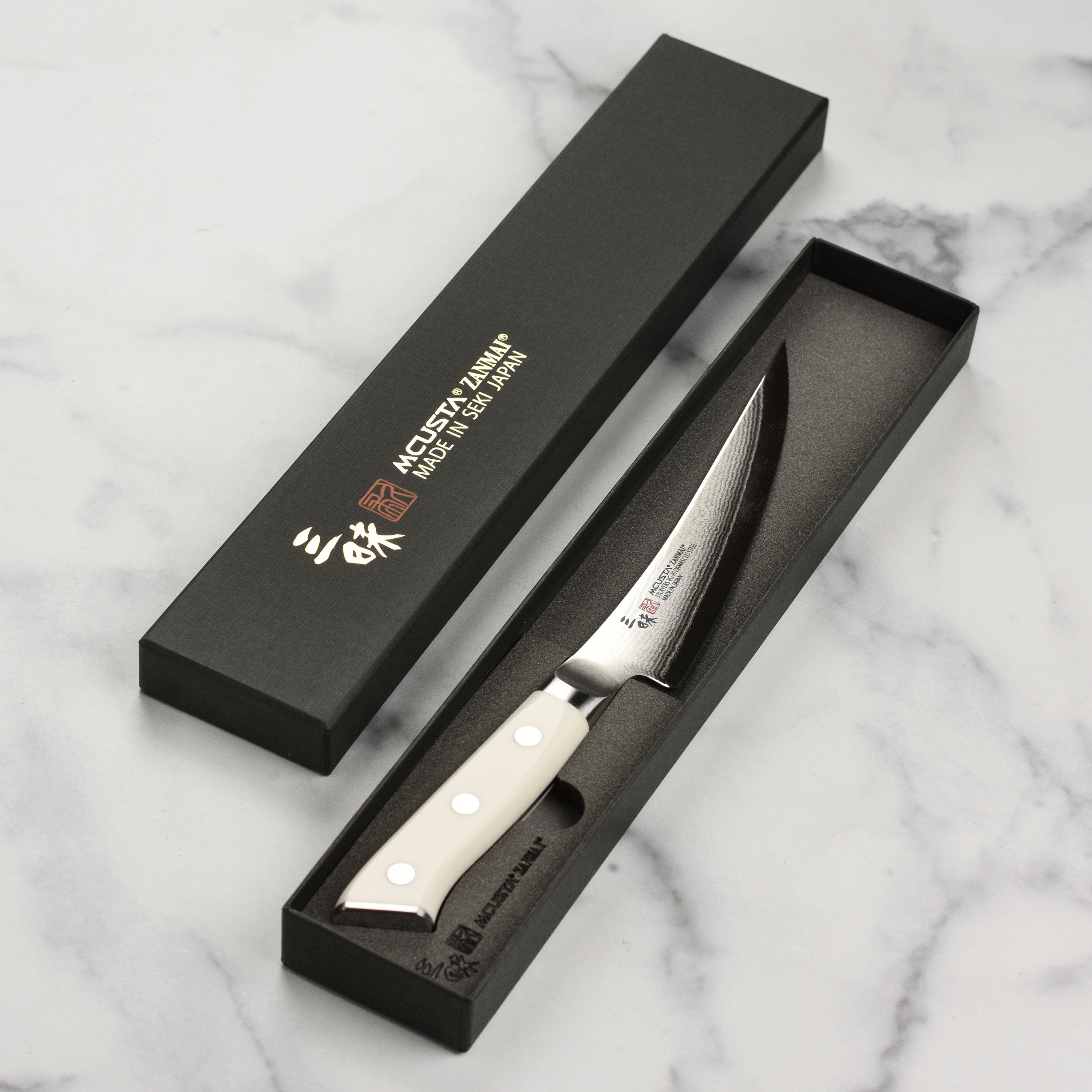 Detailed image of the Corian handle and engraved end cap of the Zanmai knife.