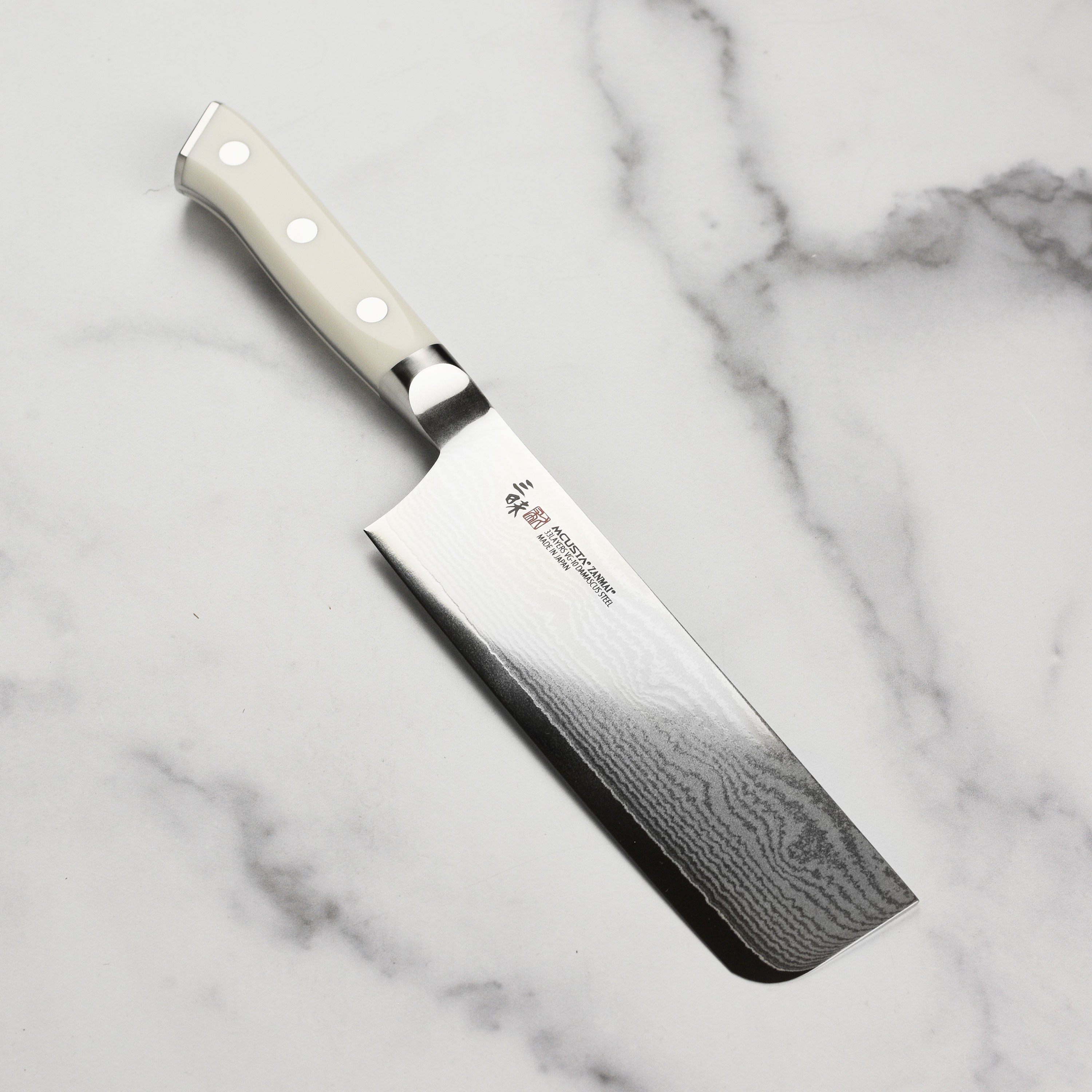 Zanmai Ultimate Damascus Nakiri Knife from the side, showcasing its sharp blade and handle.