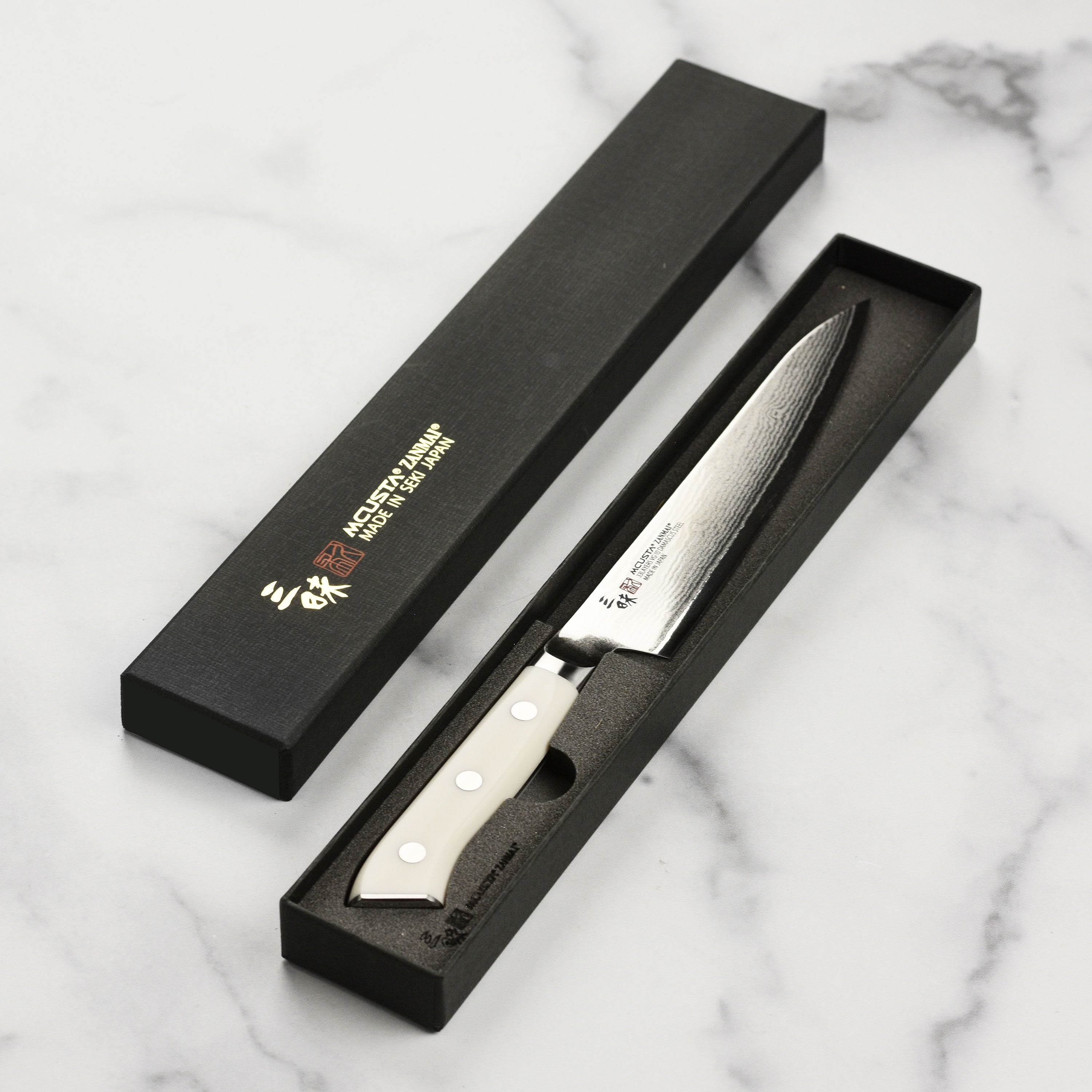 Zanmai Damascus Petty Knife in use, slicing vegetables with precision in a professional kitchen.