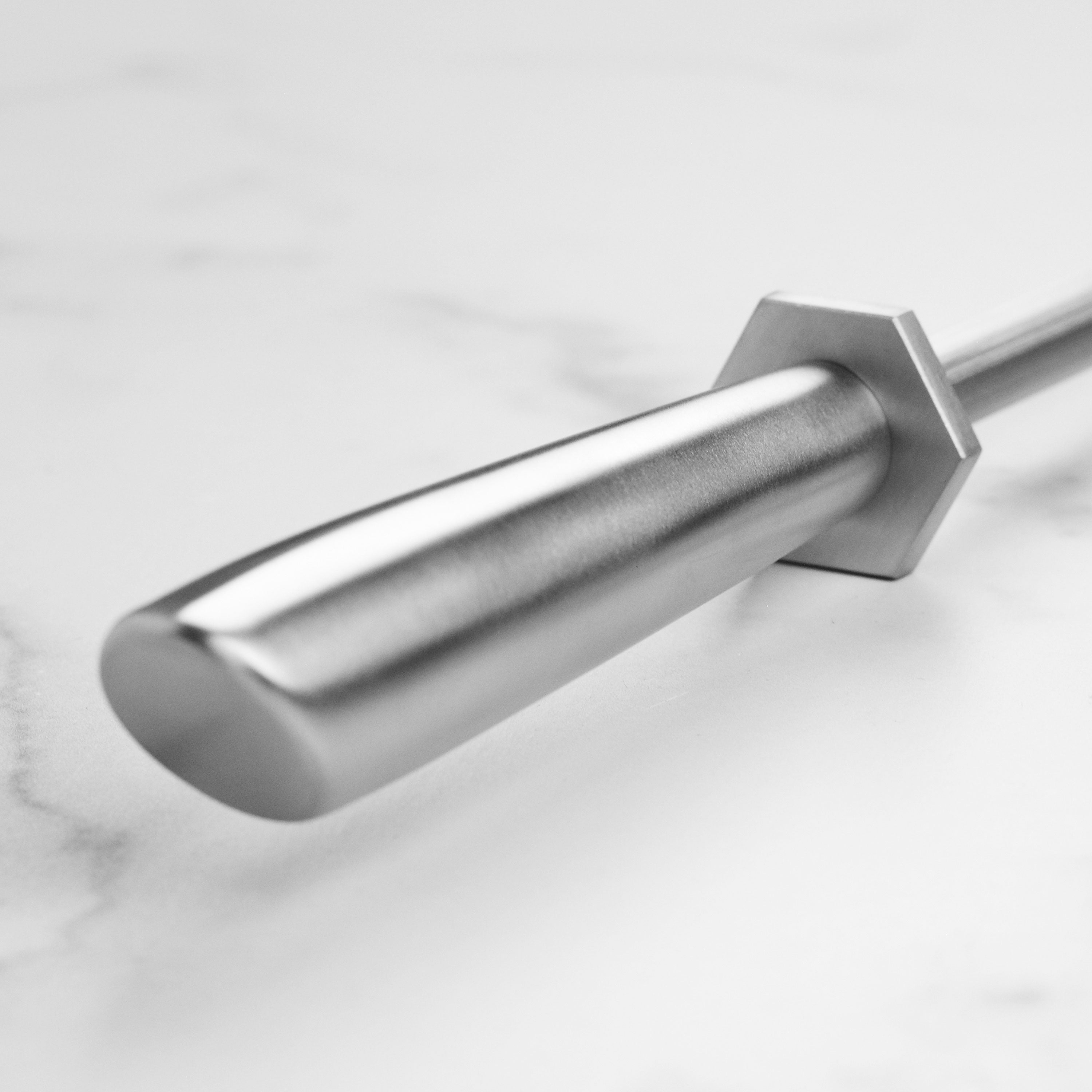 Close-up of Yaxell honing steel in action, aligning the edge of a kitchen knife.