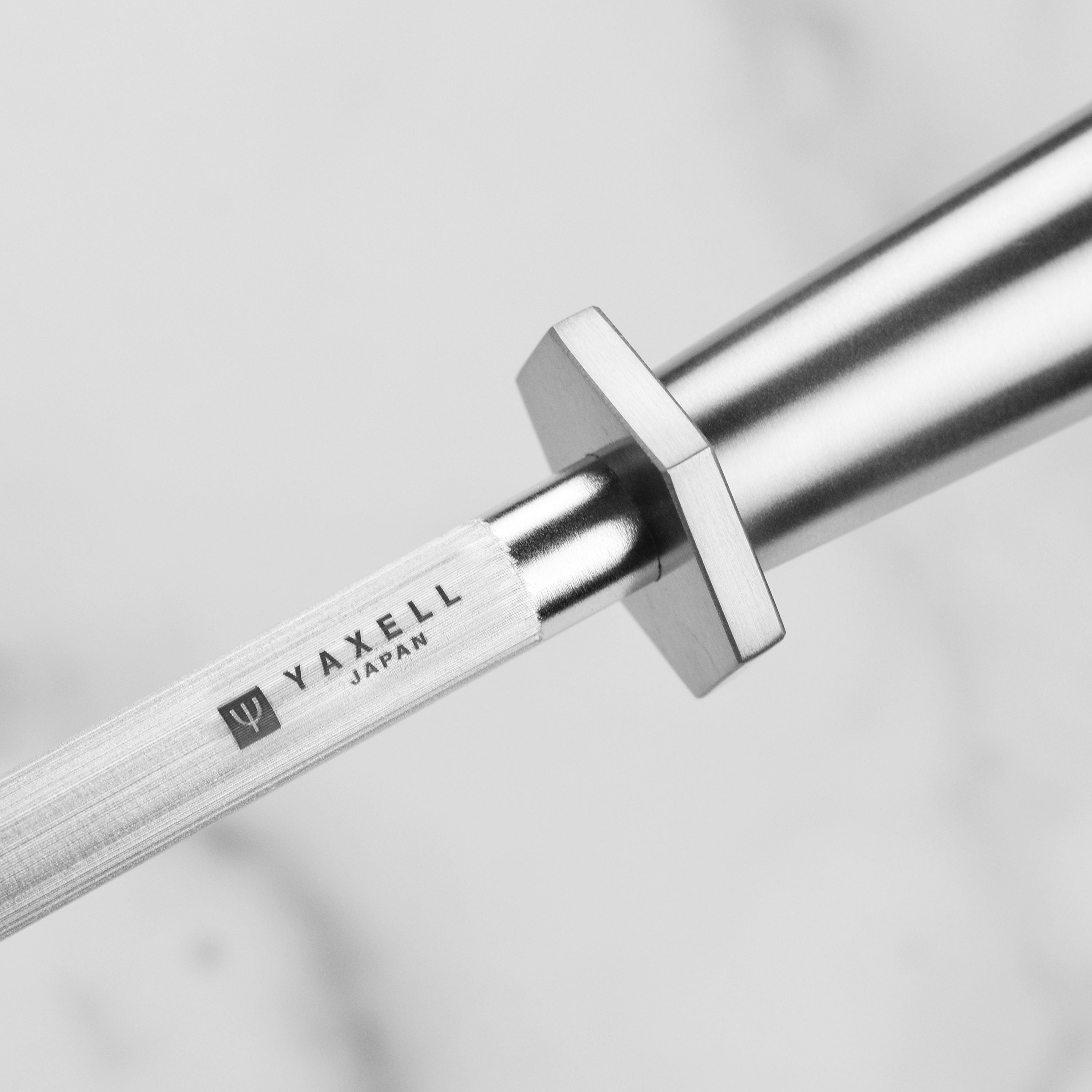Close-up of Yaxell honing steel in action, aligning the edge of a kitchen knife.