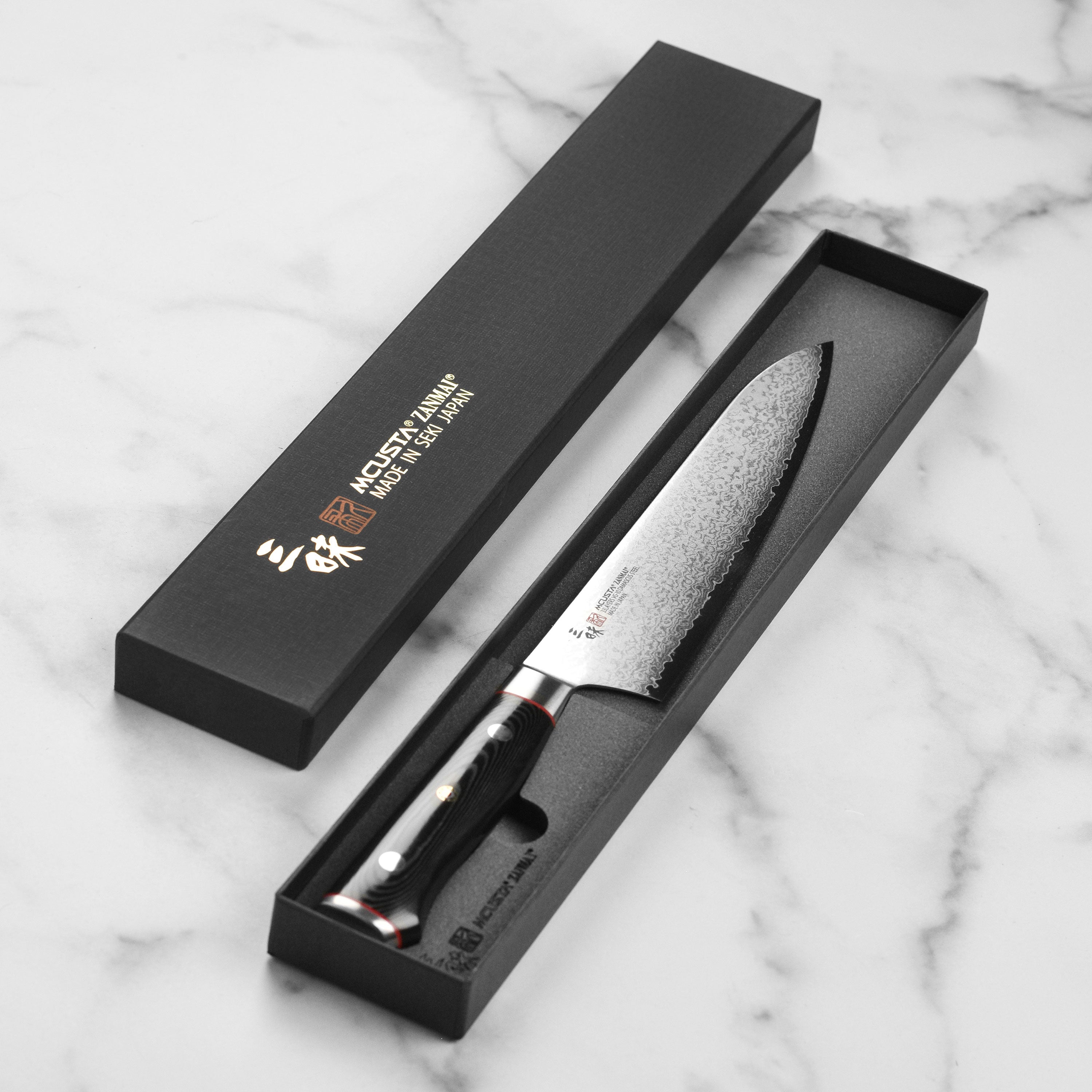 Handcrafted Zanmai Damascus steel kitchen knife with sleek black Micarta handle and mosaic pin