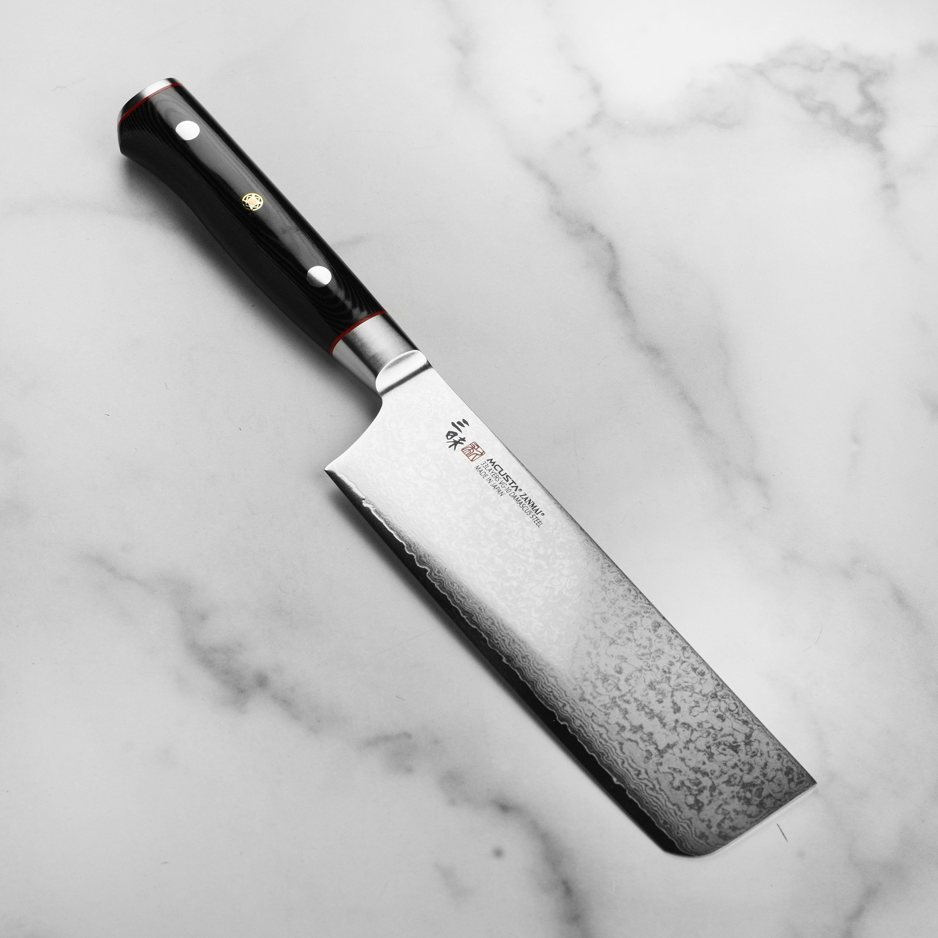 Close-up of Damascus nakiri knife blade showing 33-layer steel pattern and VG10 core