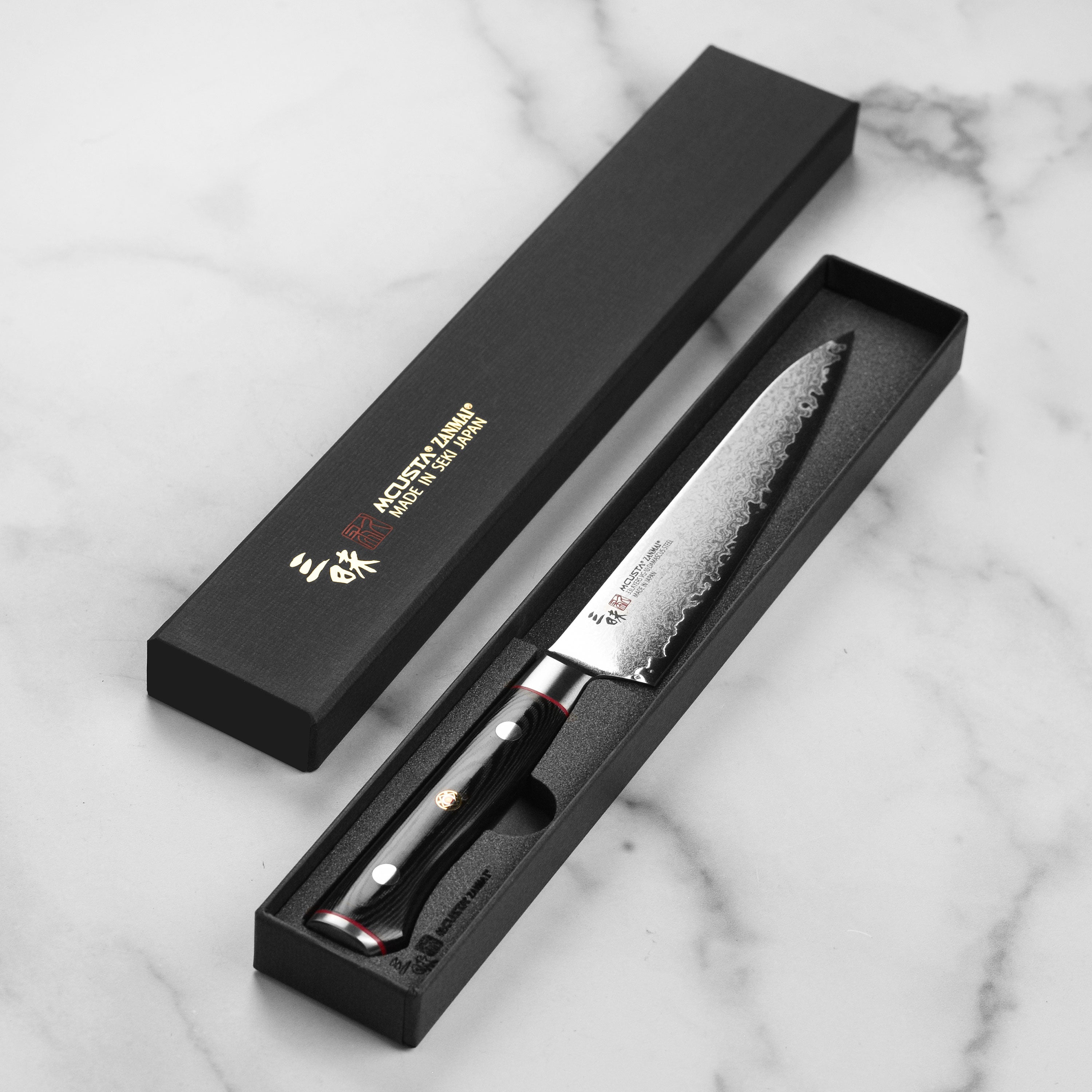 Ergonomic black Micarta handle with red spacers on the Zanmai chef knife