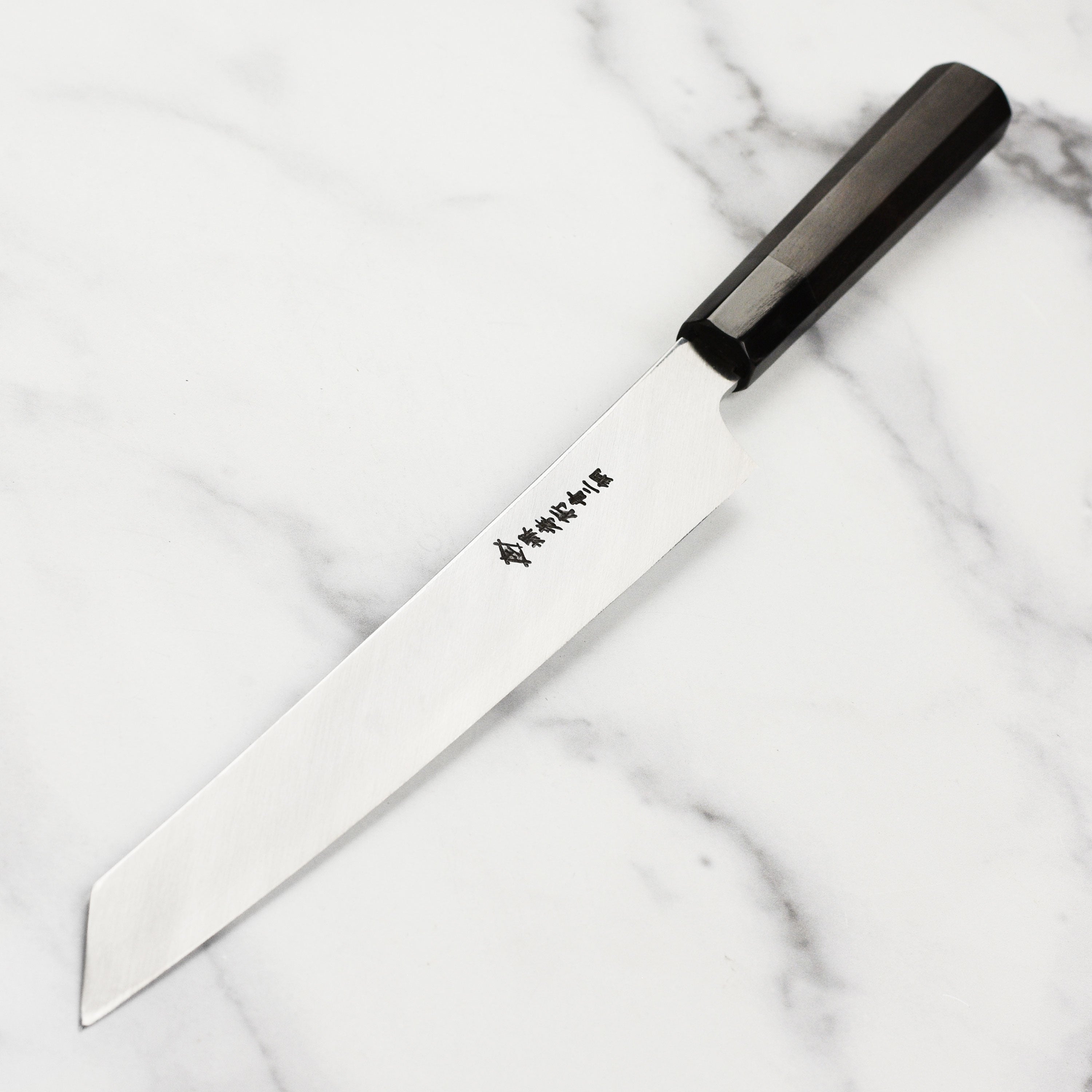 Detailed view of the high carbon steel blade, highlighting mirror finish and sharp edge