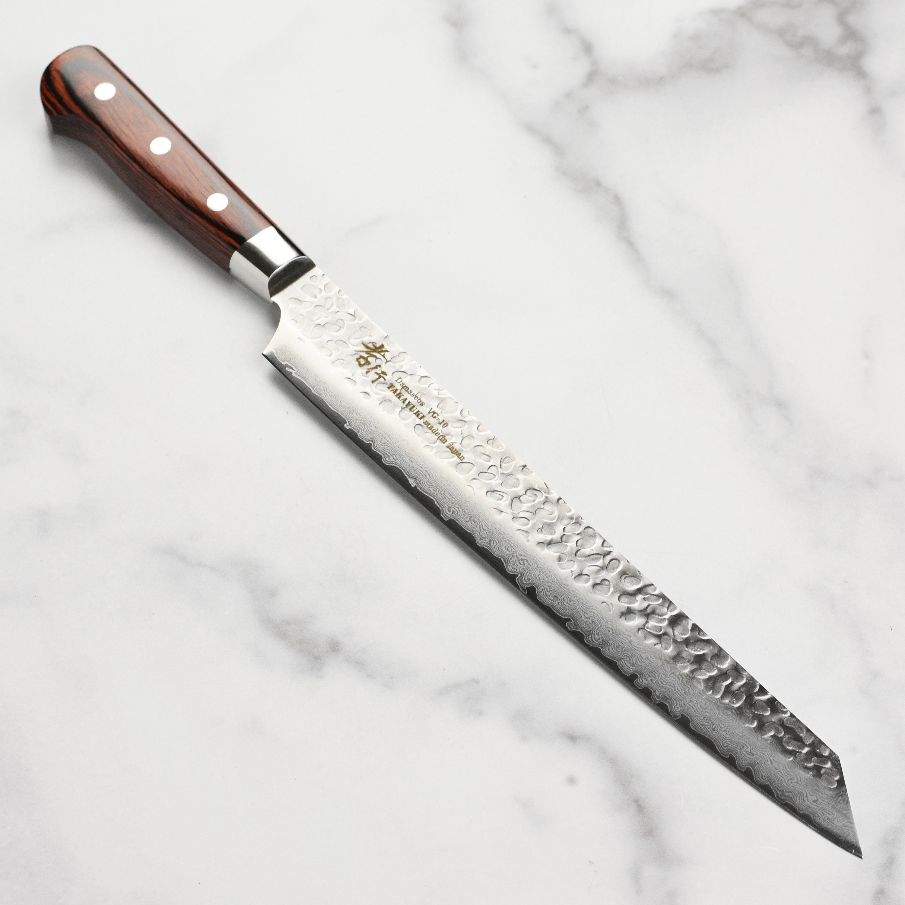 Sakai Takayuki Hammered Damascus Knife on a wooden cutting board, showcasing its sleek design.
