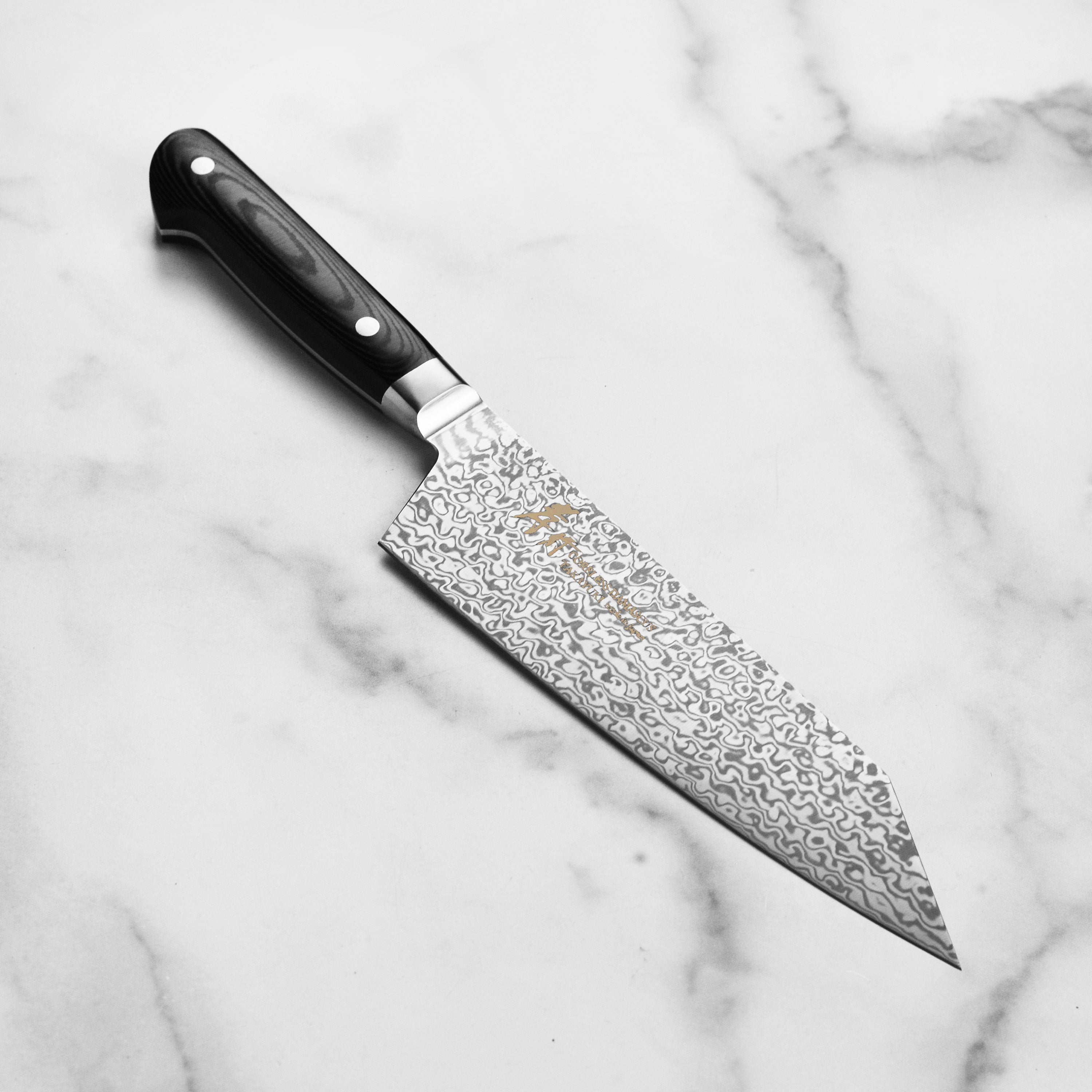 Close-up of Takayuki Damascus knife showing layered steel patterns and razor-sharp edge