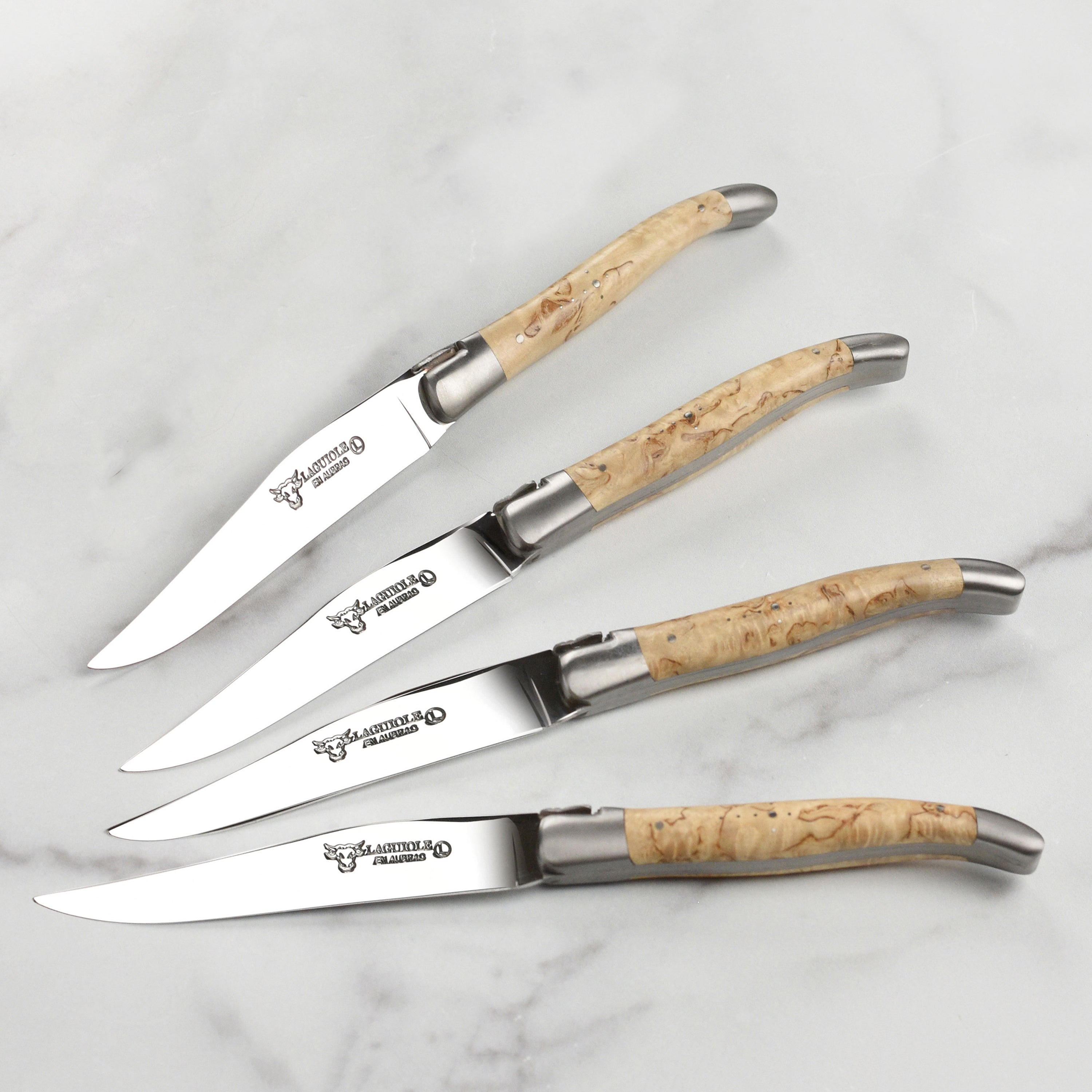 Close-up of the sharp stainless steel blade and birchwood handle of a Laguiole knife.