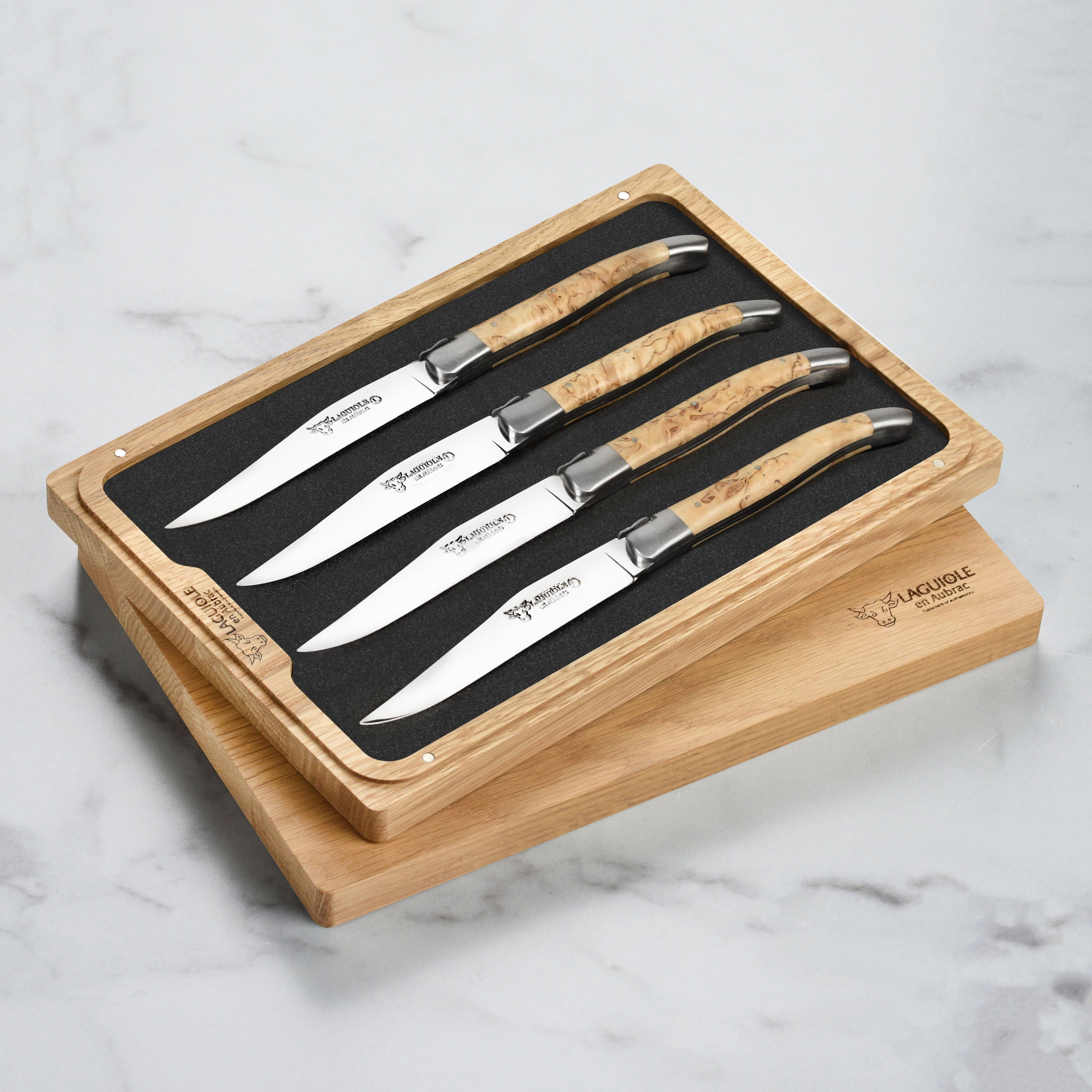 Laguiole en Aubrac steak knives set with birchwood handles on a dining table.