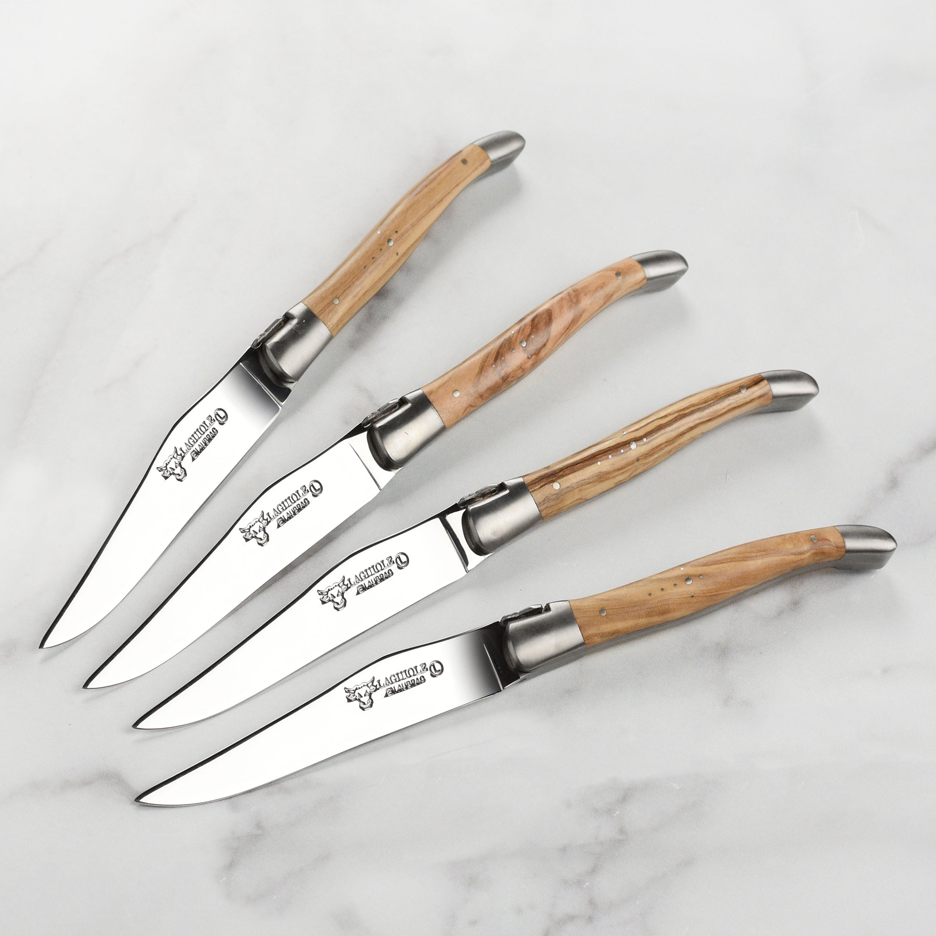 Set of four stainless steel steak knives with olive wood handles on a dining table