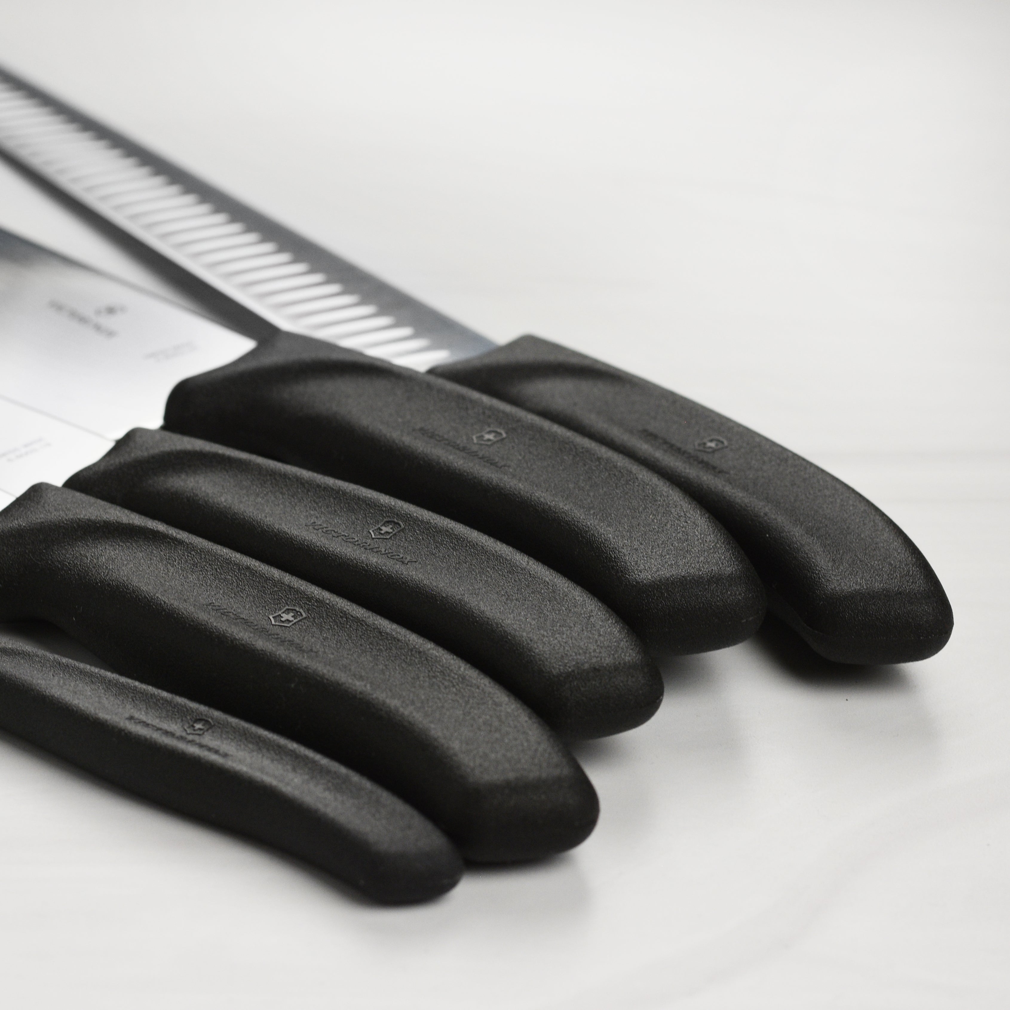The complete Swiss Precision 7-Piece BBQ Knife Collection displayed on a wooden cutting board.