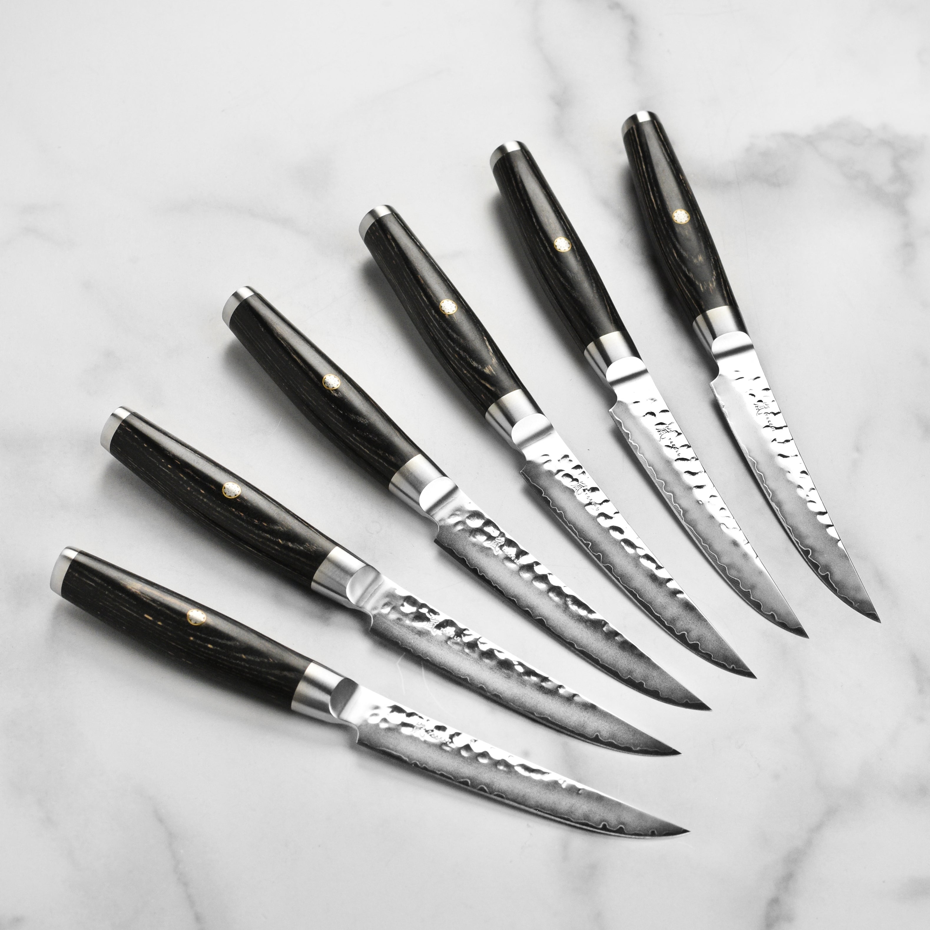 Close-up of hammered Japanese chef knives with black pakkawood handles