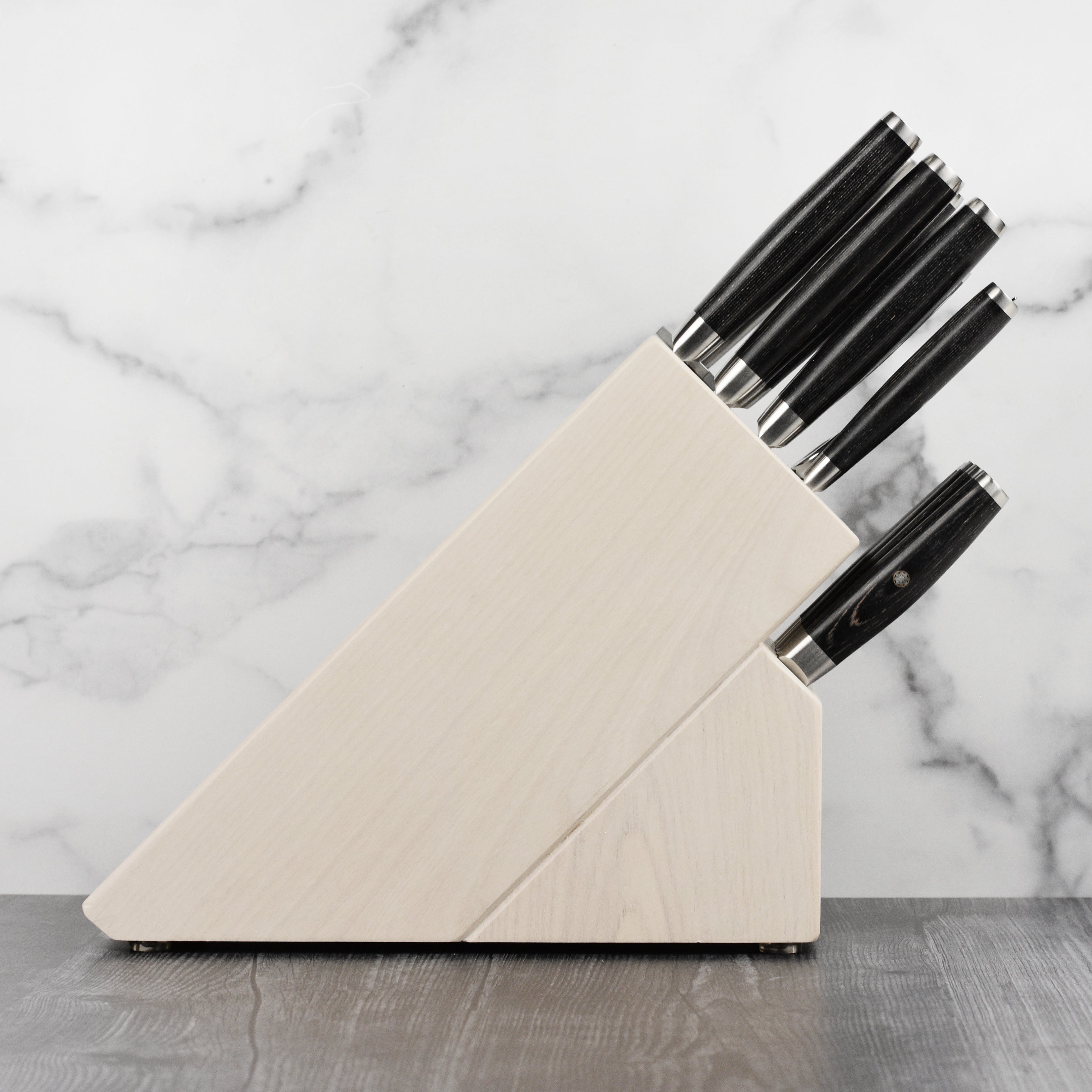 Japanese kitchen knife set displayed on a wooden countertop with a cutting board
