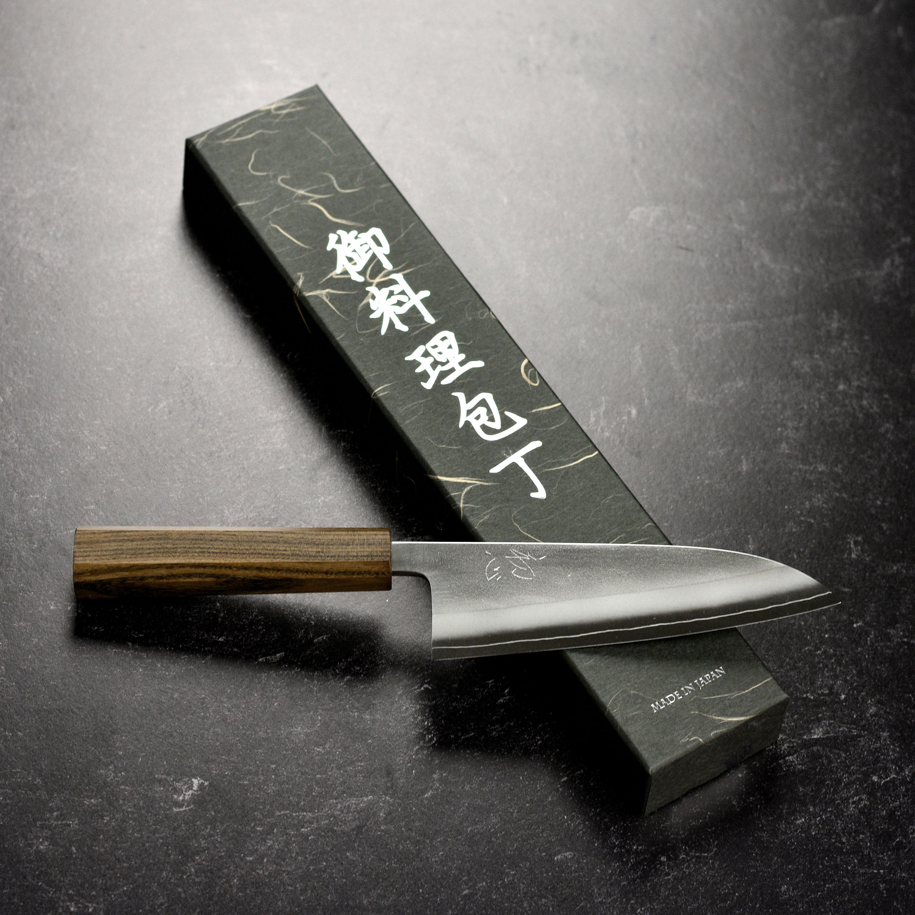 Overview of the Yoshikane Nashiji Santoku knife next to a set of fresh ingredients, highlighting its professional design.