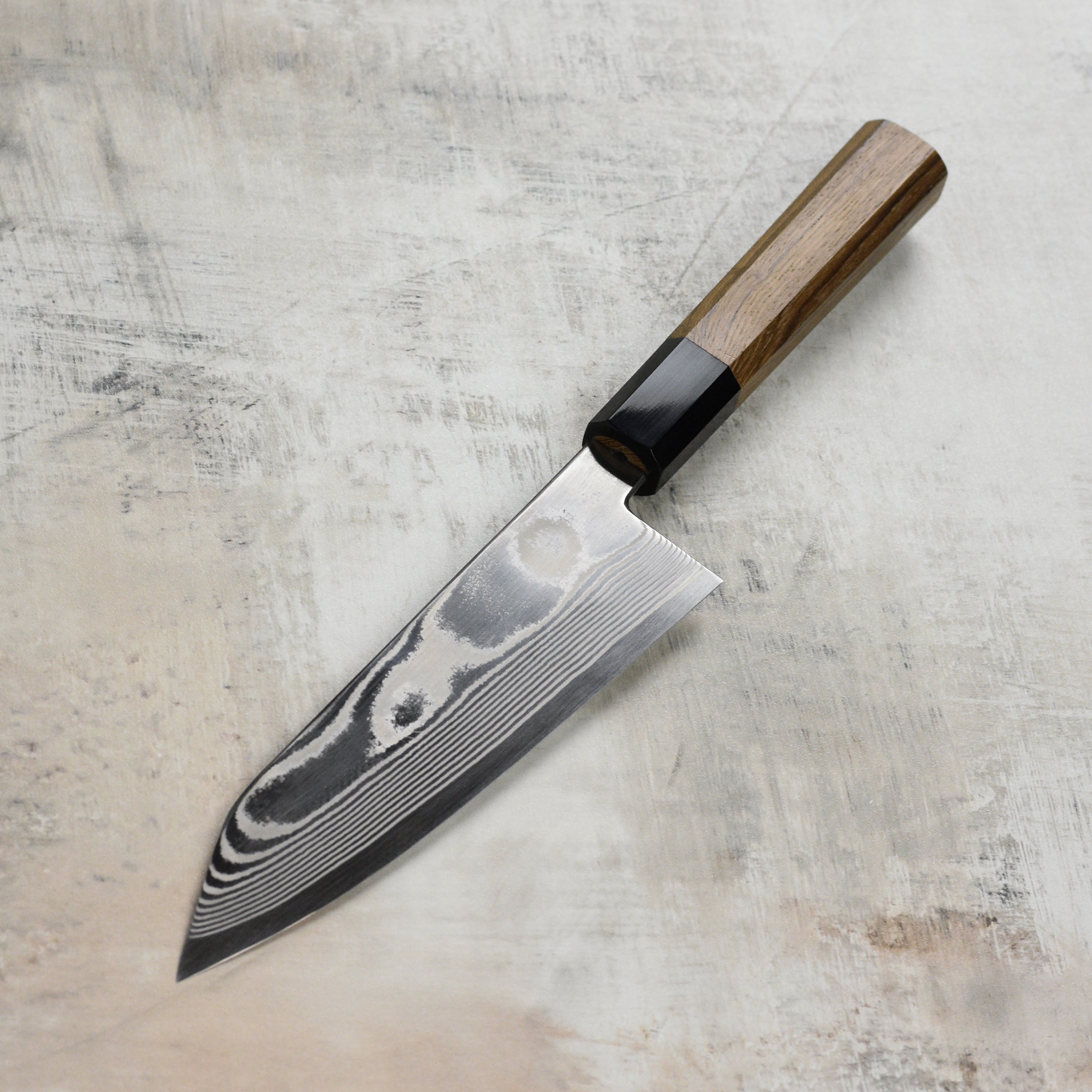 Close-up of the Hatsukokoro Ginsan Damascus knife on a wooden cutting board