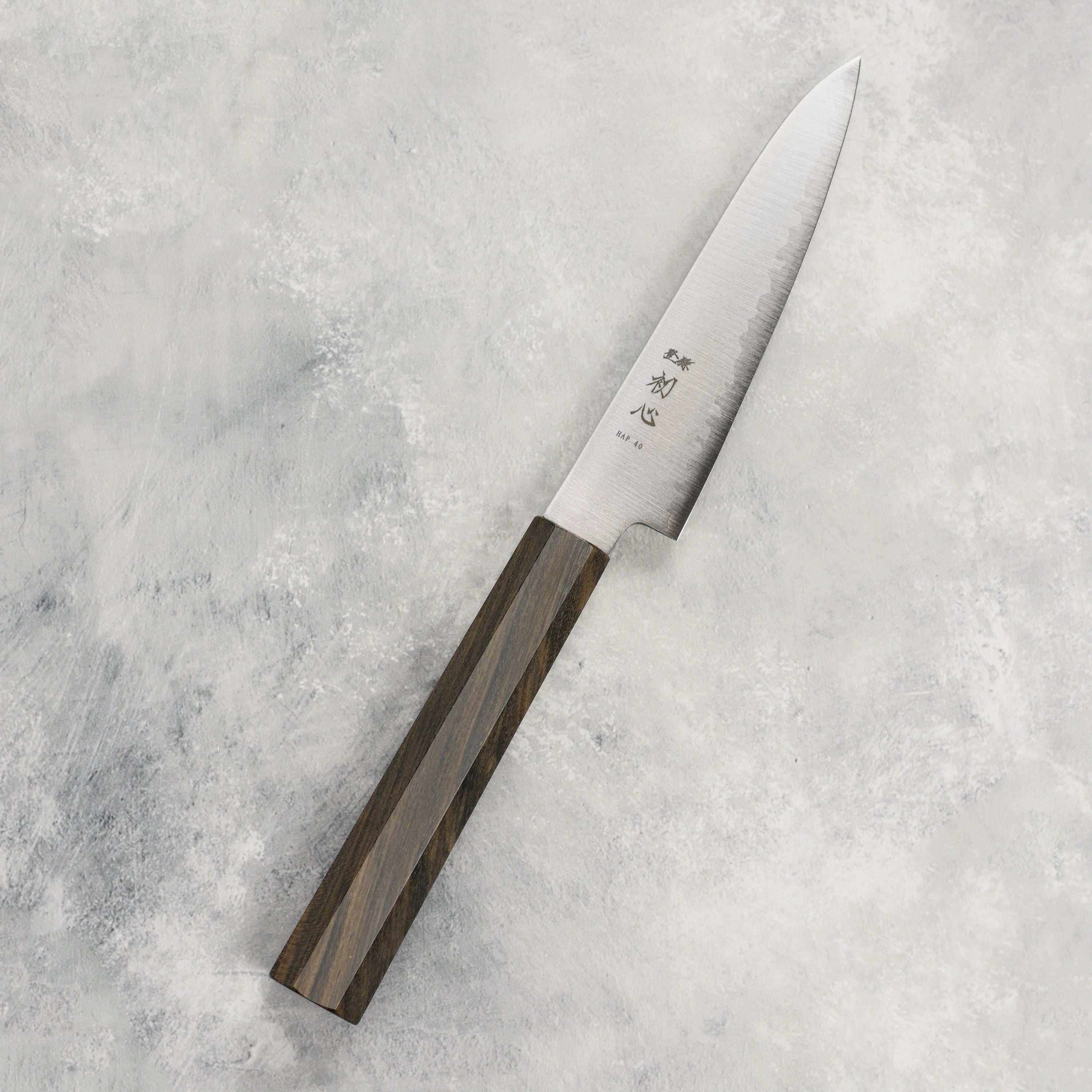 Hatsukokoro Hayabusa HAP40 4.7" Precision Petty Knife displayed on a wooden cutting board, highlighting its sharp blade and beautiful design.