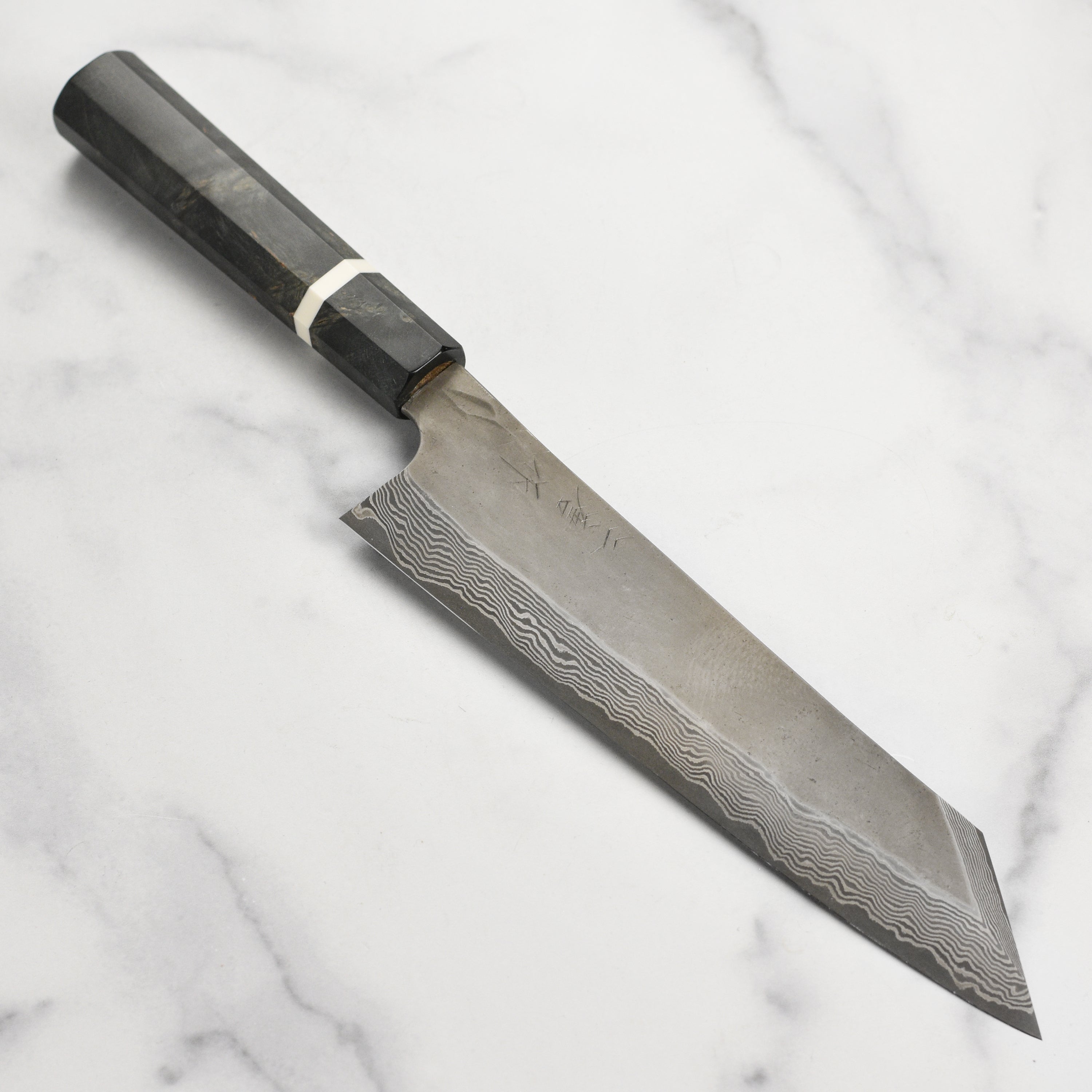Close-up of the blade of the Ginsan Damascus Kiritsuke chef knife, showcasing its intricate patterns.