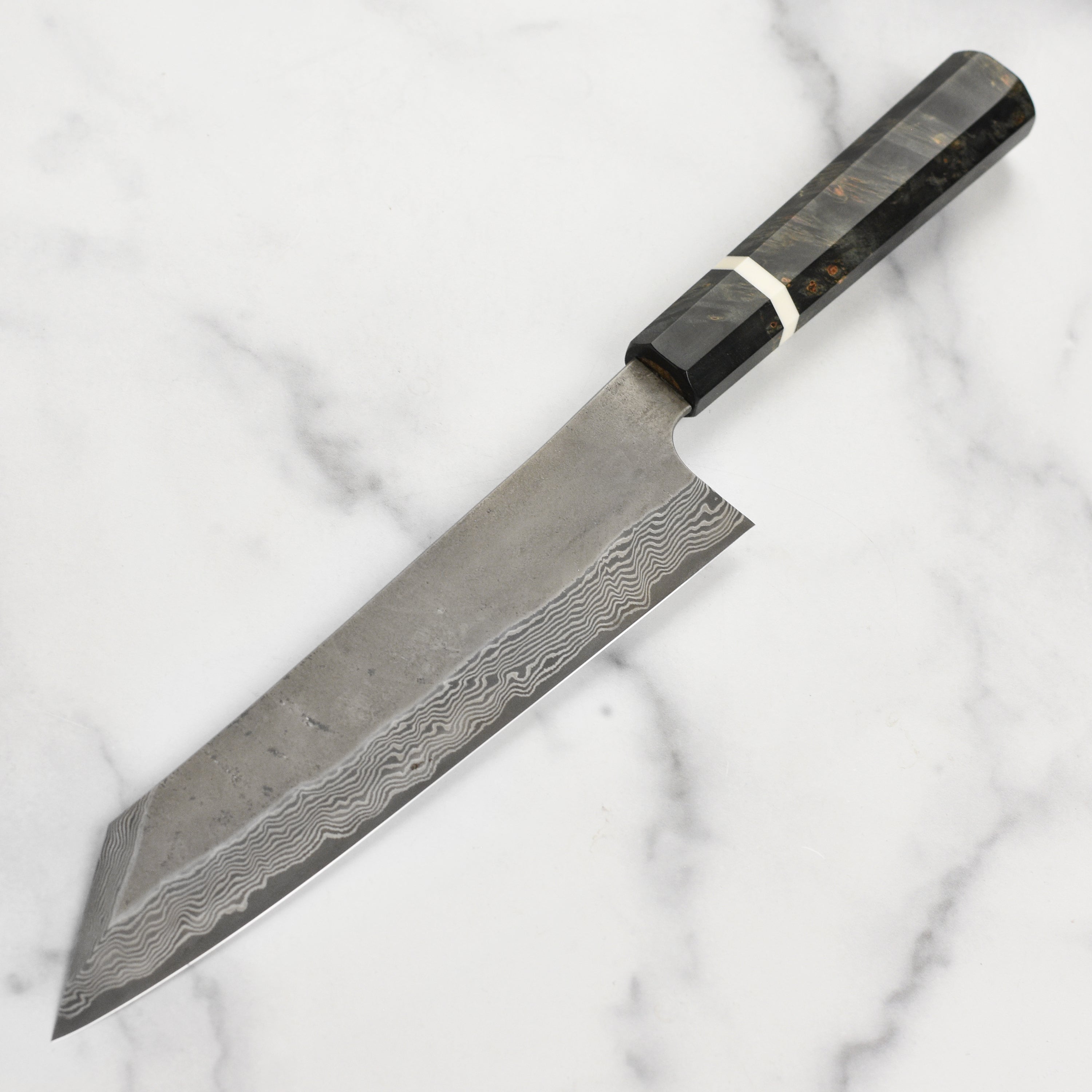 Close-up of the blade of the Ginsan Damascus Kiritsuke chef knife, showcasing its intricate patterns.