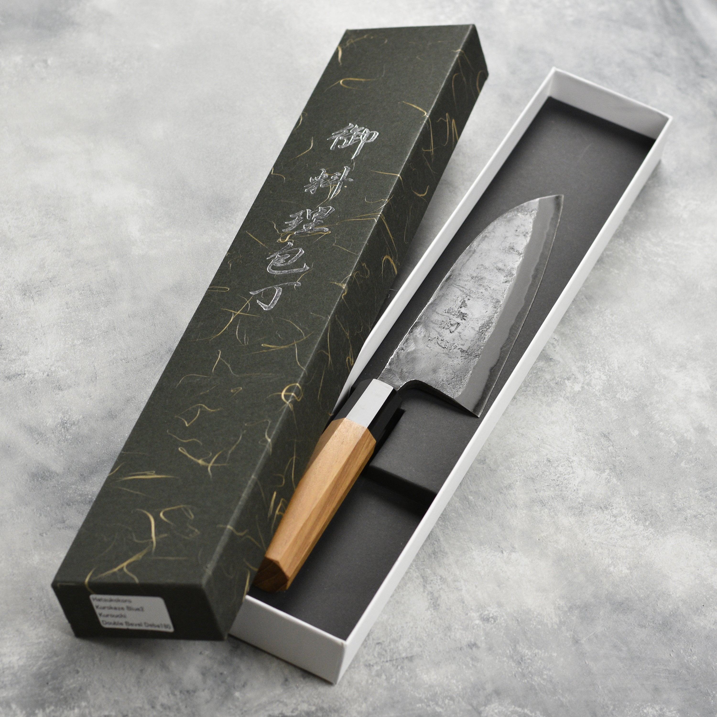 Hatsukokoro Kurokaze Aogami 7" Deba knife on a wooden cutting board, showcasing its elegant design.