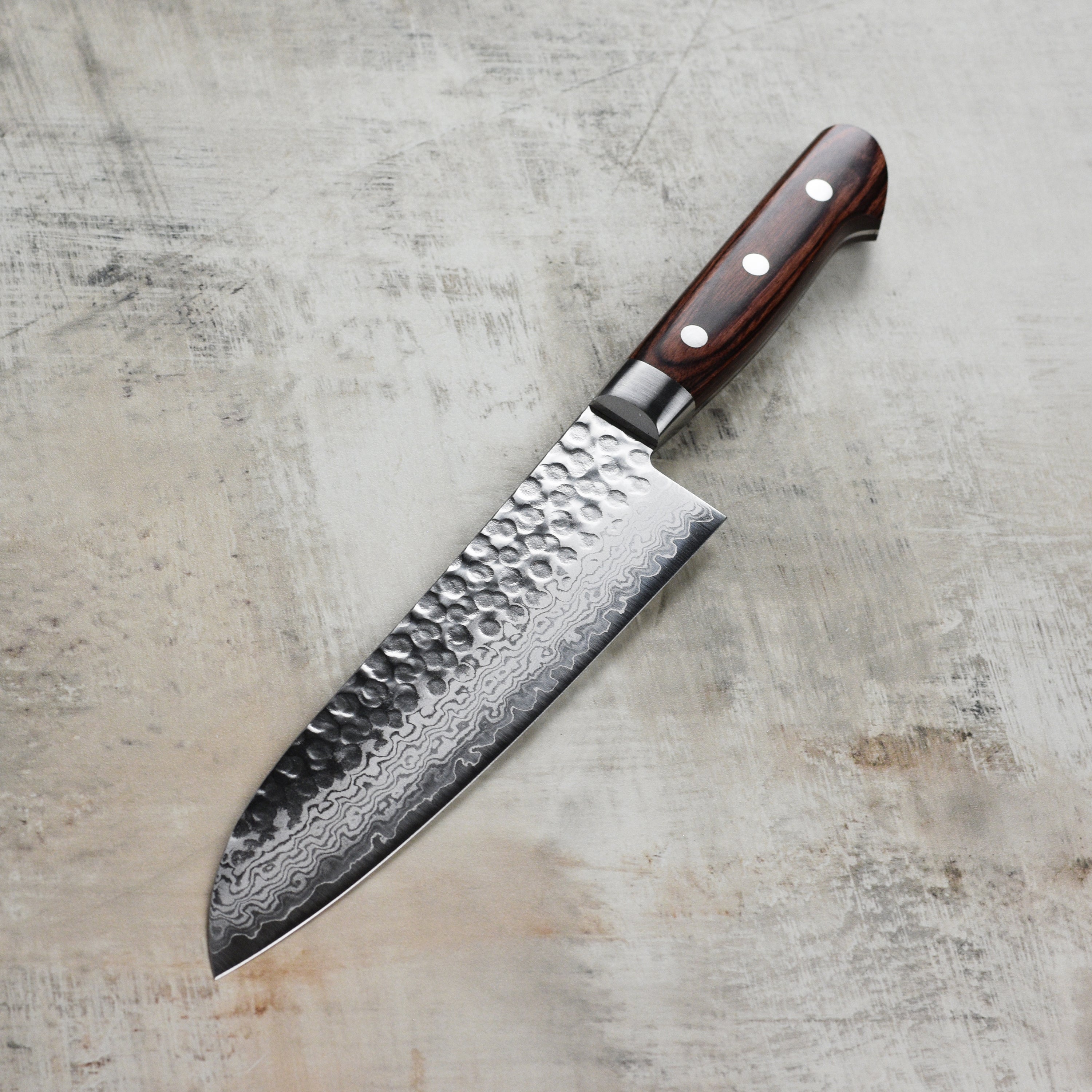 Ittetsu VG10 Premium Hammered Damascus Santoku Knife displayed on a wooden cutting board, highlighting its beautiful design.