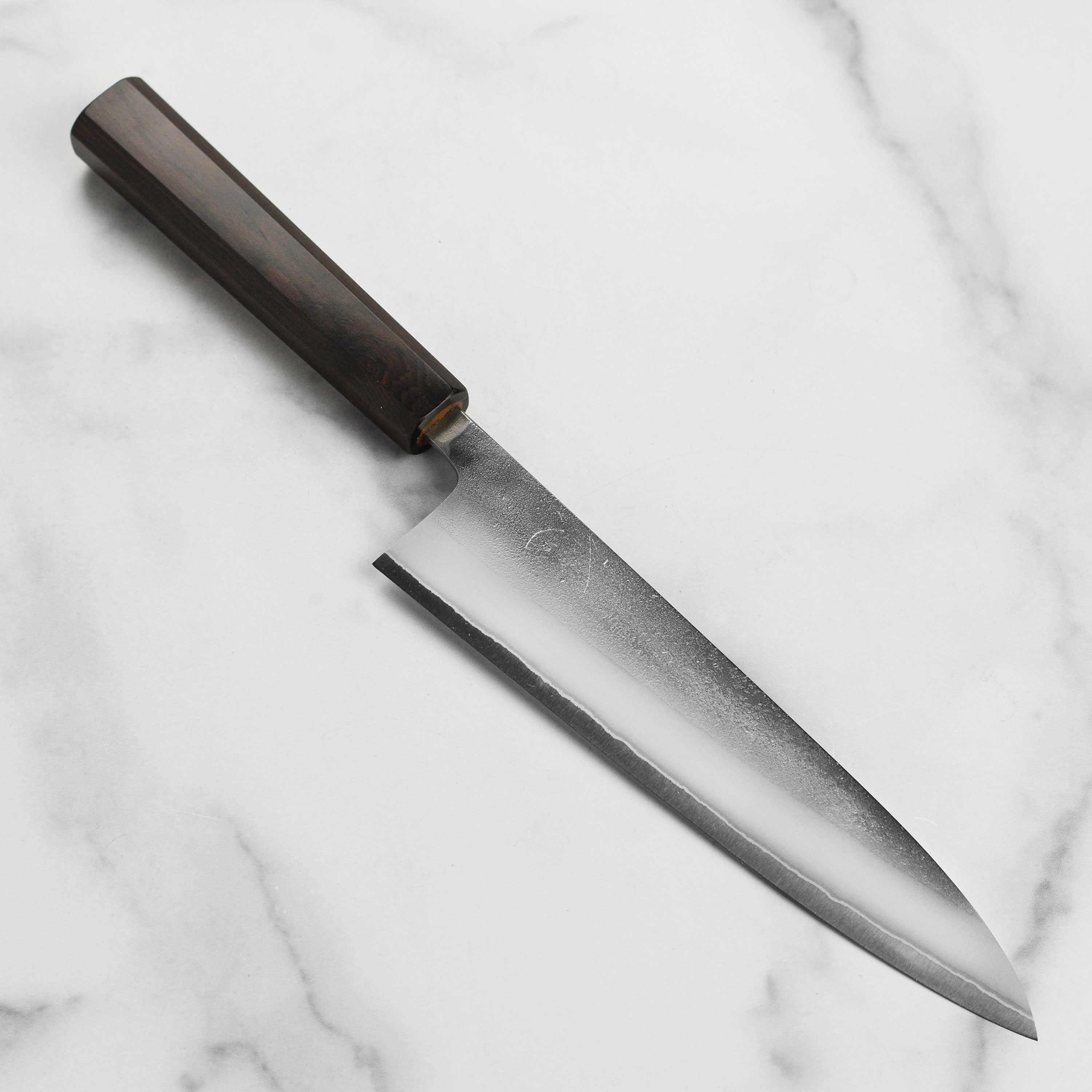 Yoshikane Shirogami #2 Nashiji Gyuto knife with ebony handle on a wooden cutting board