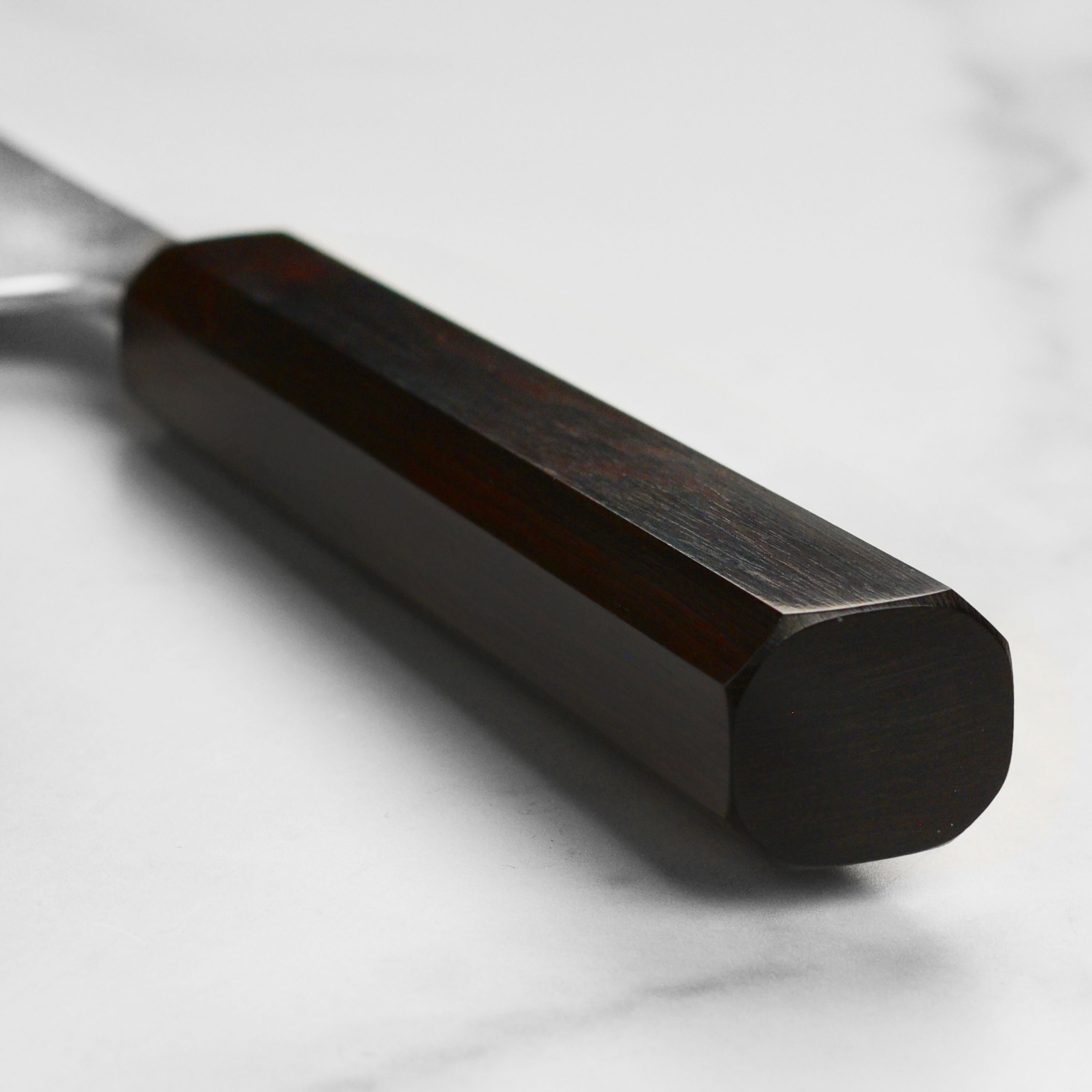 Japanese gyuto knife slicing vegetables on a cutting board, focus on blade