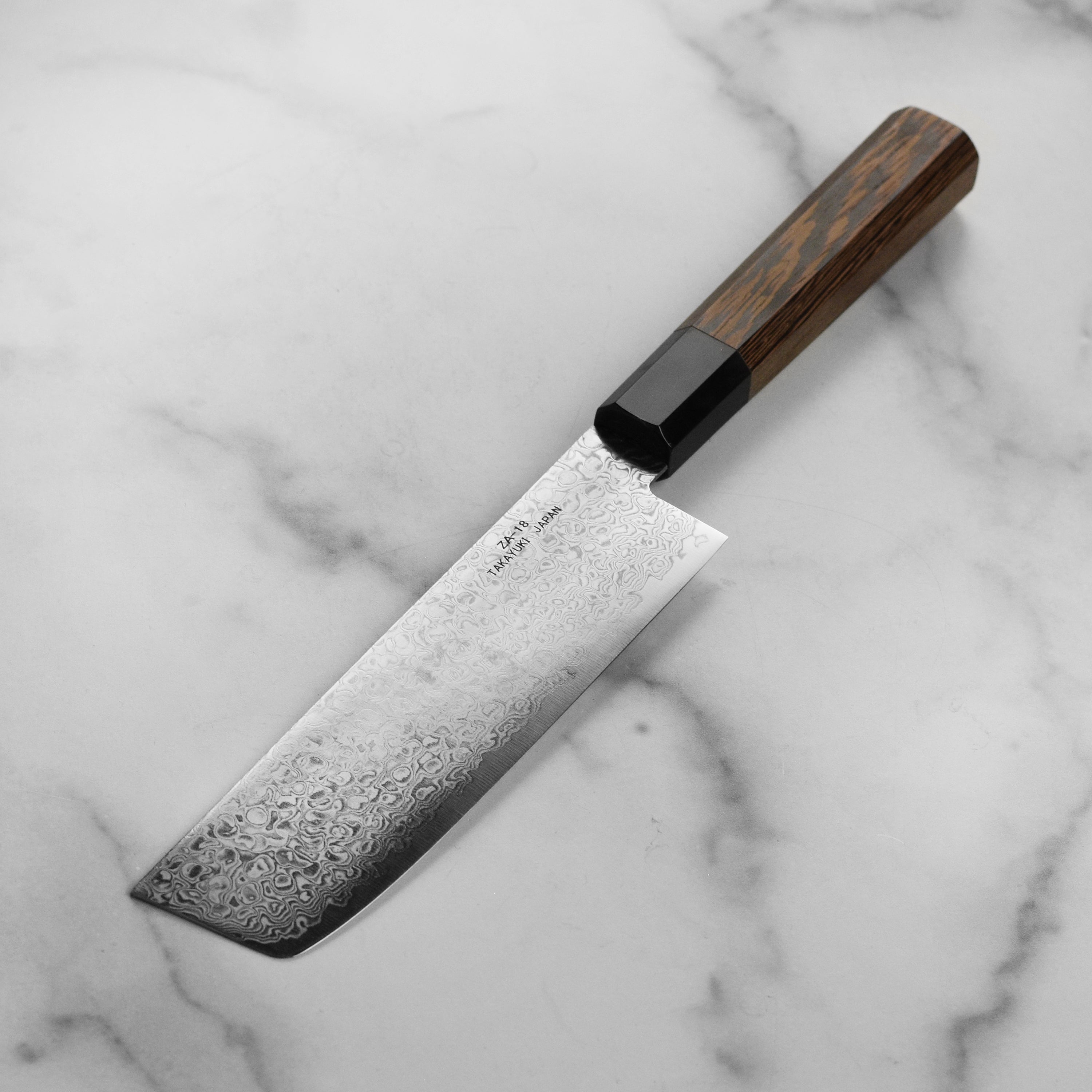 Takayuki Ginga Nakiri knife in action, cutting fresh vegetables on a wooden board.
