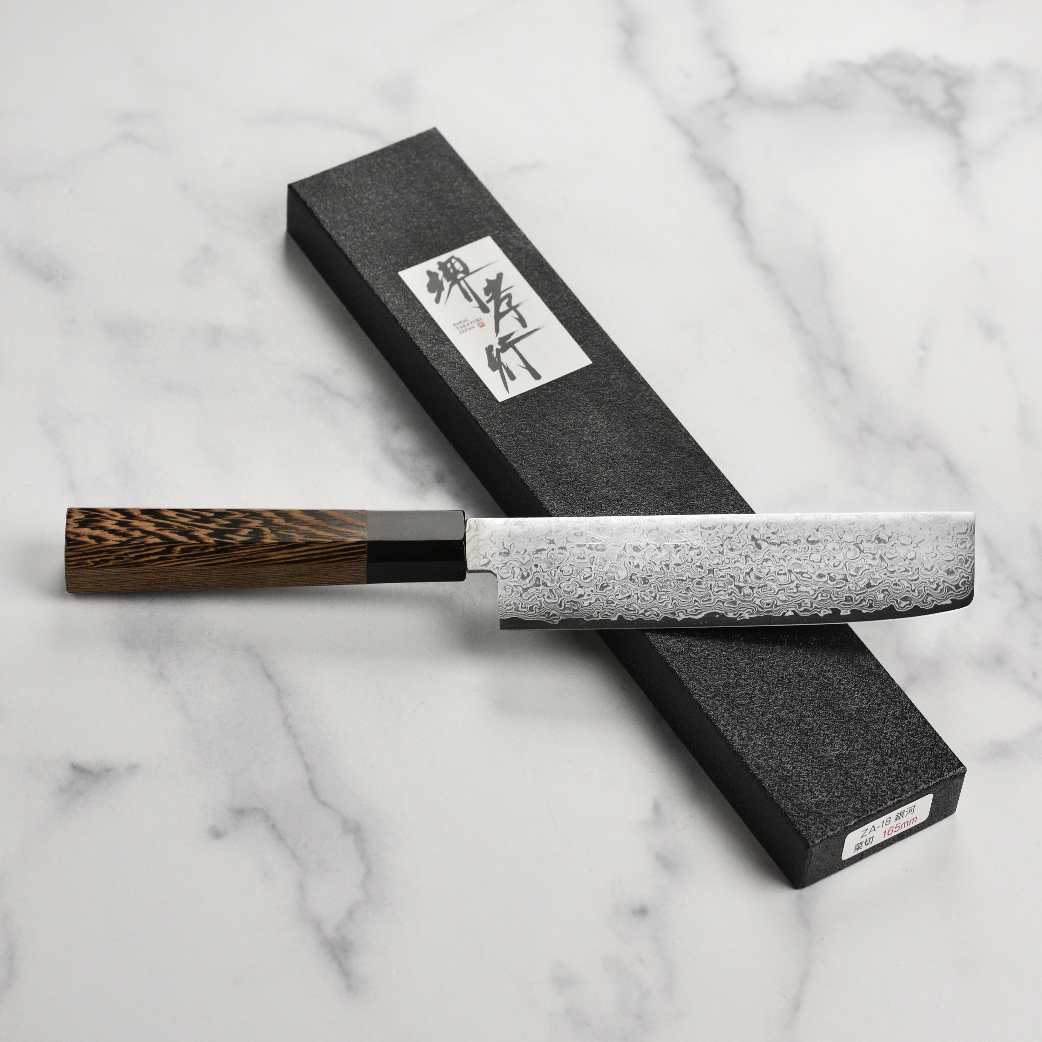 Takayuki Ginga Nakiri knife in action, cutting fresh vegetables on a wooden board.