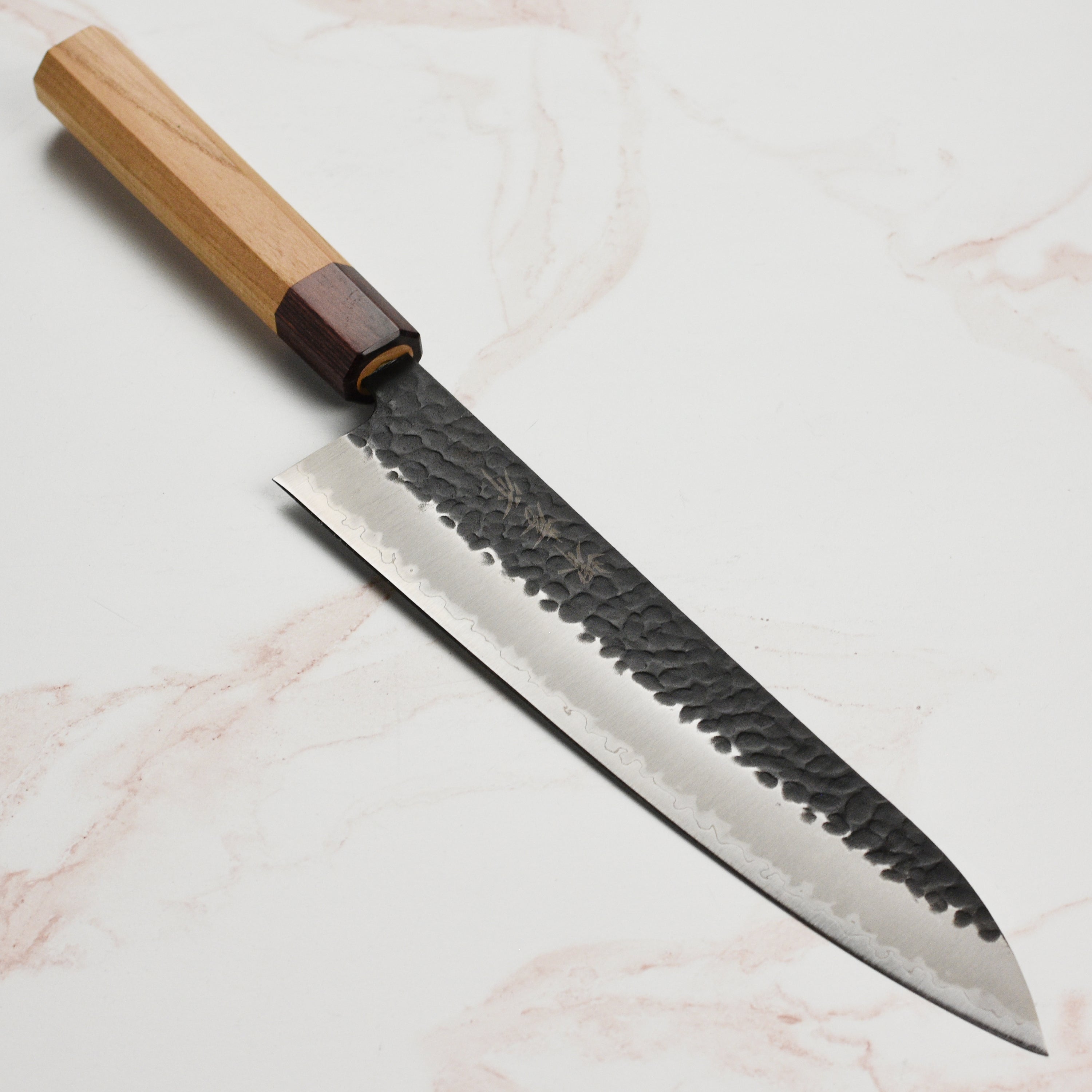 Close-up of Takayuki Aogami Super Gyuto knife showcasing the blue carbon steel blade and hammered finish.