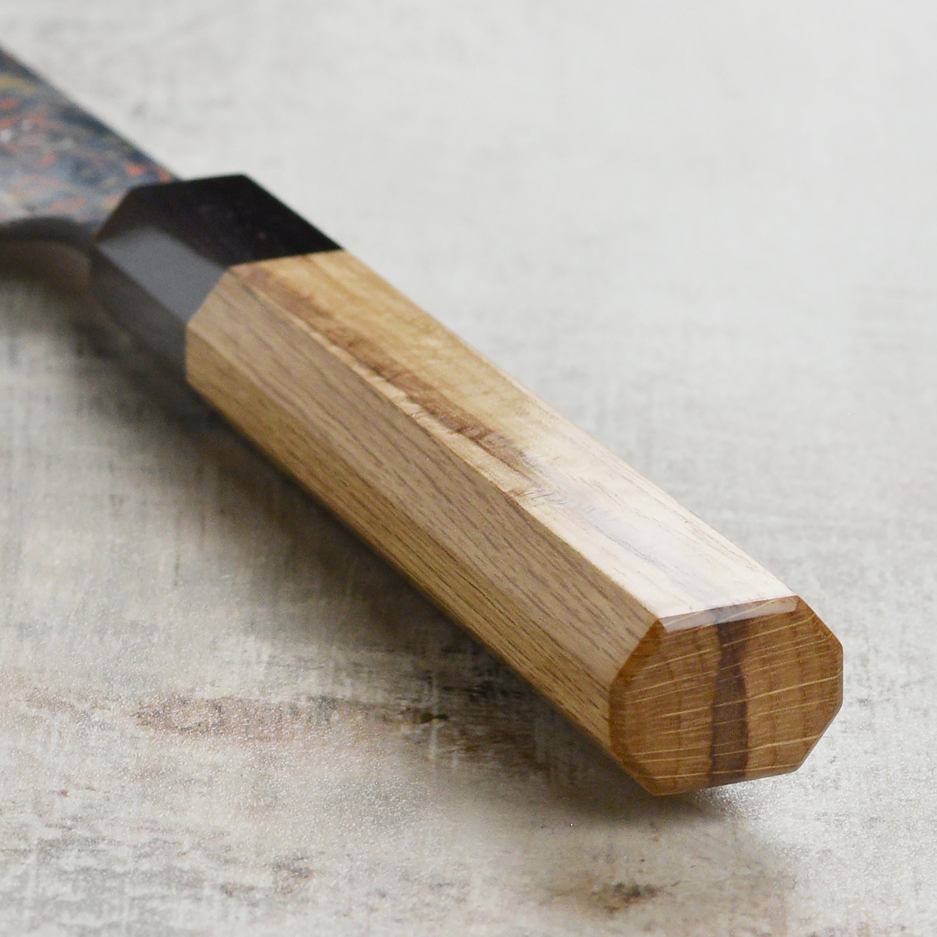 Japanese chef slicing fish with a Damascus sujihiki knife in a professional kitchen