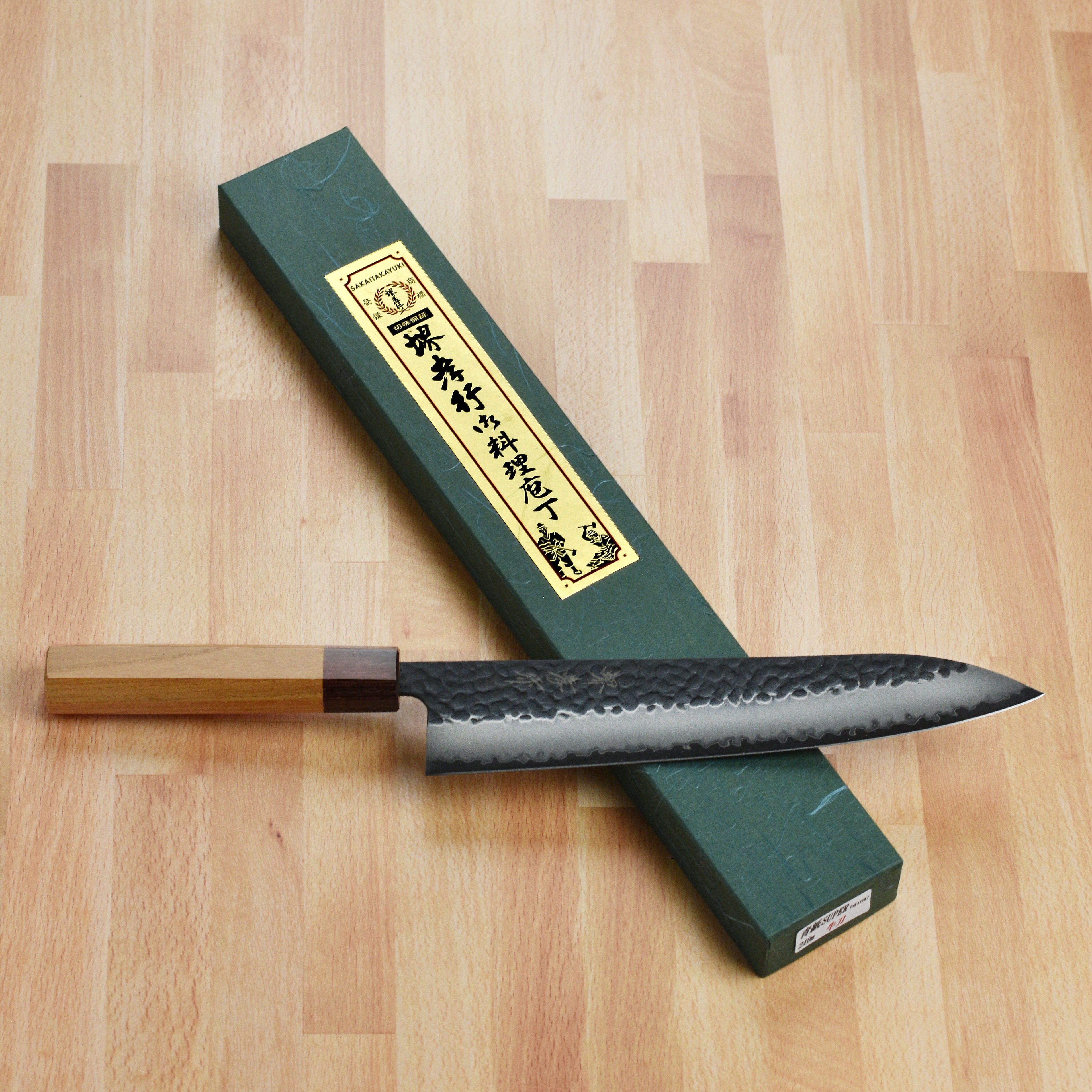 Elegant display of the Takayuki Aogami Super Gyuto knife highlighting the Zelkova wood handle and mahogany ferrule.