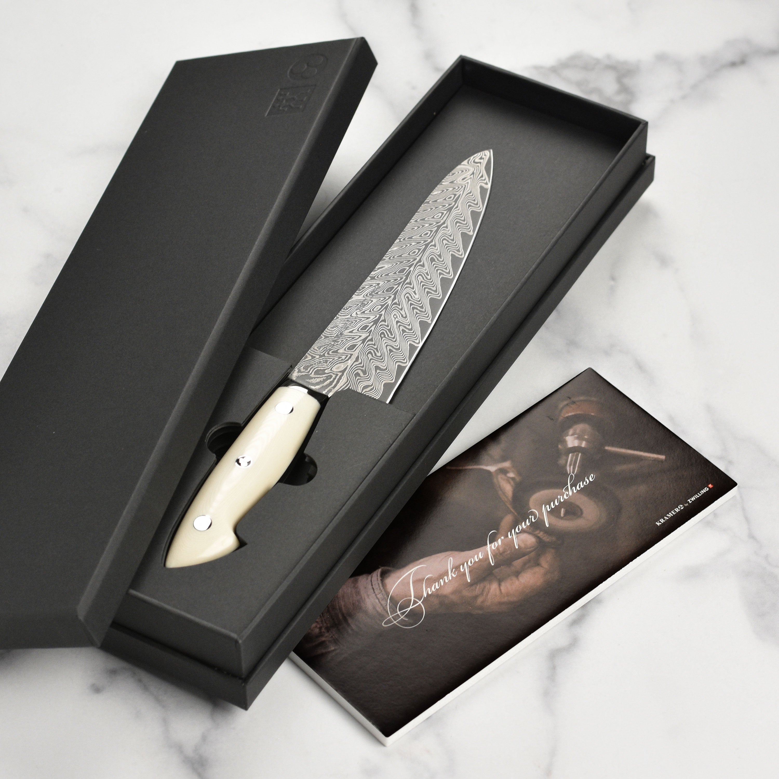 Kramer Cumulus 7" Santoku Knife showcasing the damascus pattern and micarta handle from a side angle.
