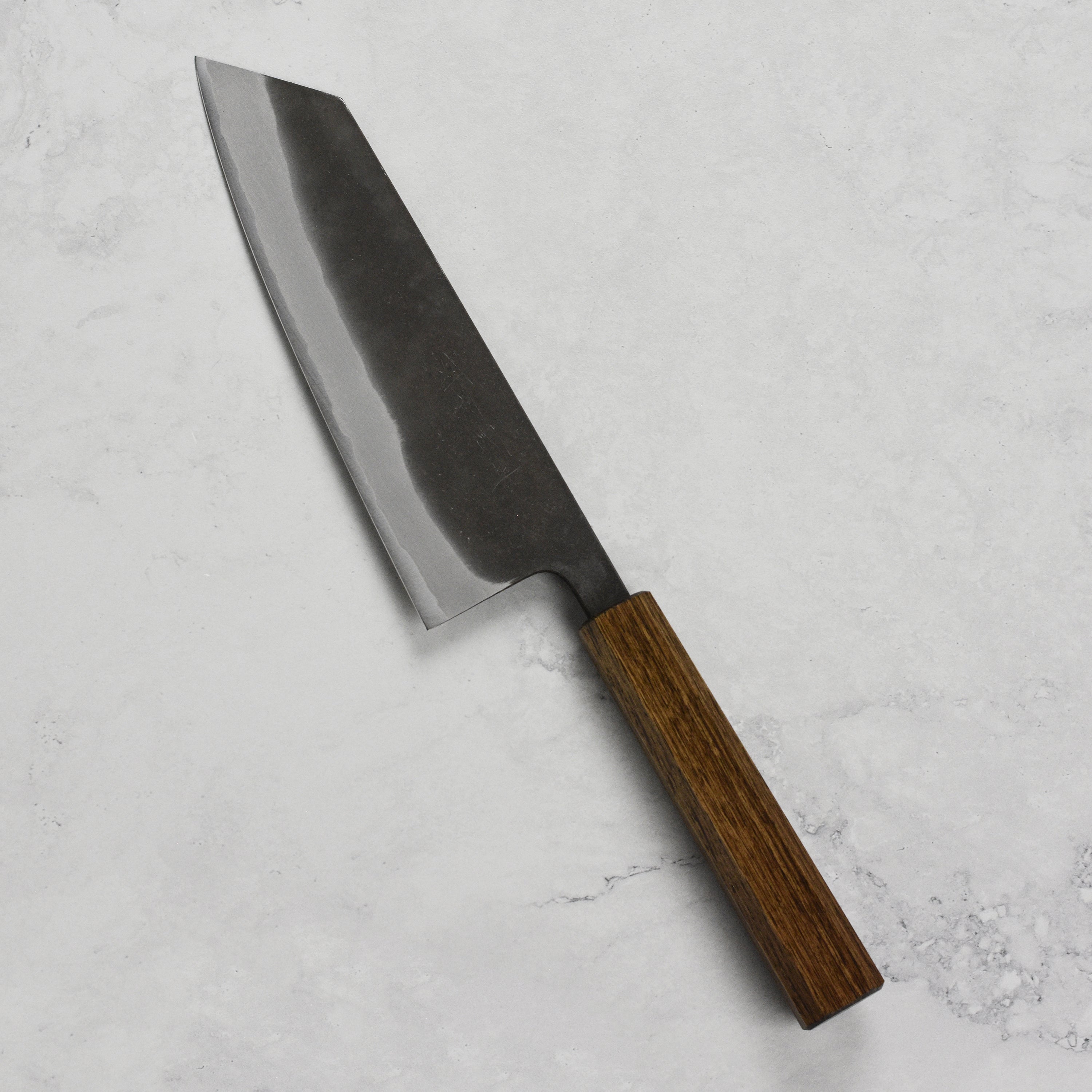 Shiro Kamo Aogami Bunka knife in action, slicing fresh vegetables on a wooden cutting board.