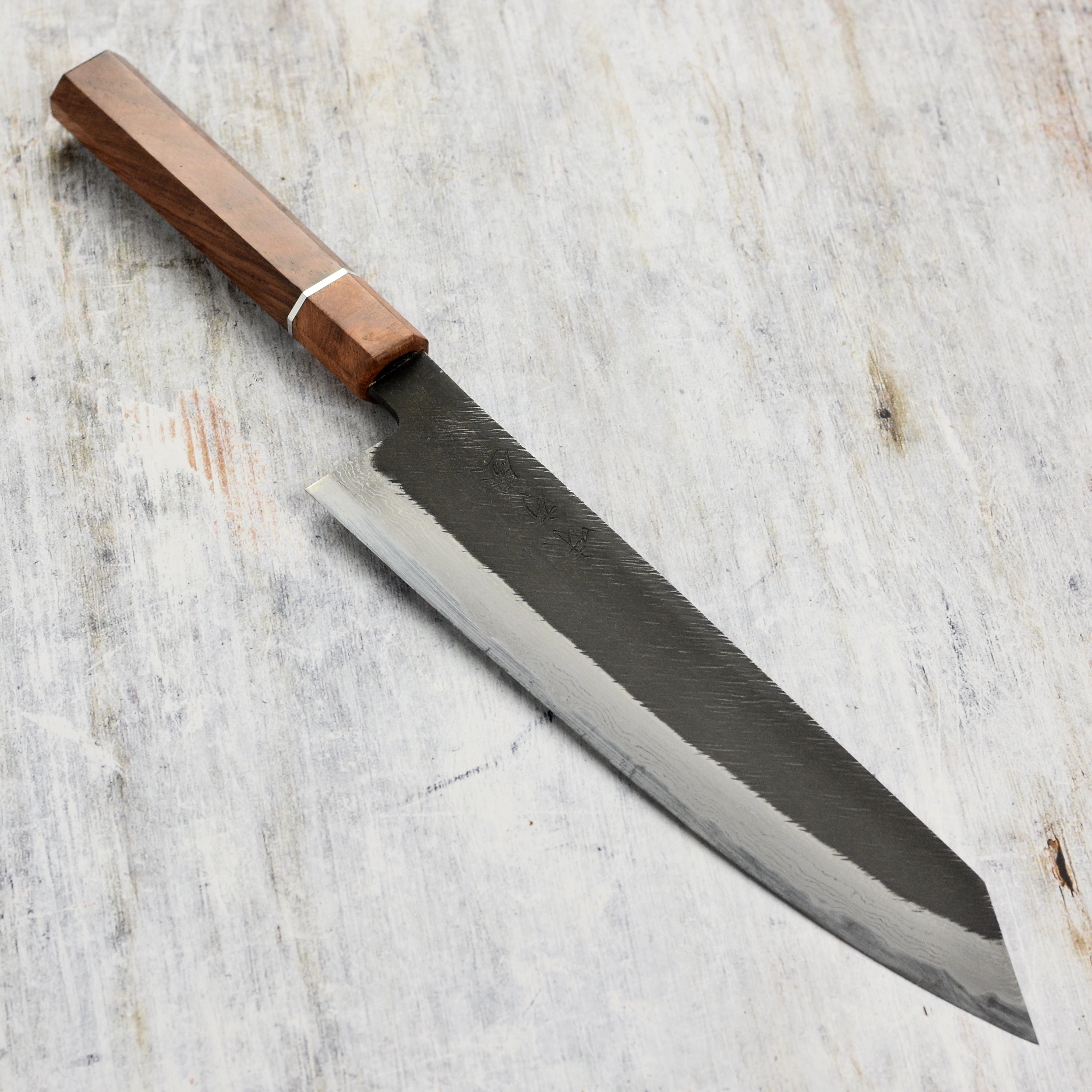 Premium Shirogami kiritsuke knife showcasing its sharp blade and ergonomic handle from a side angle.