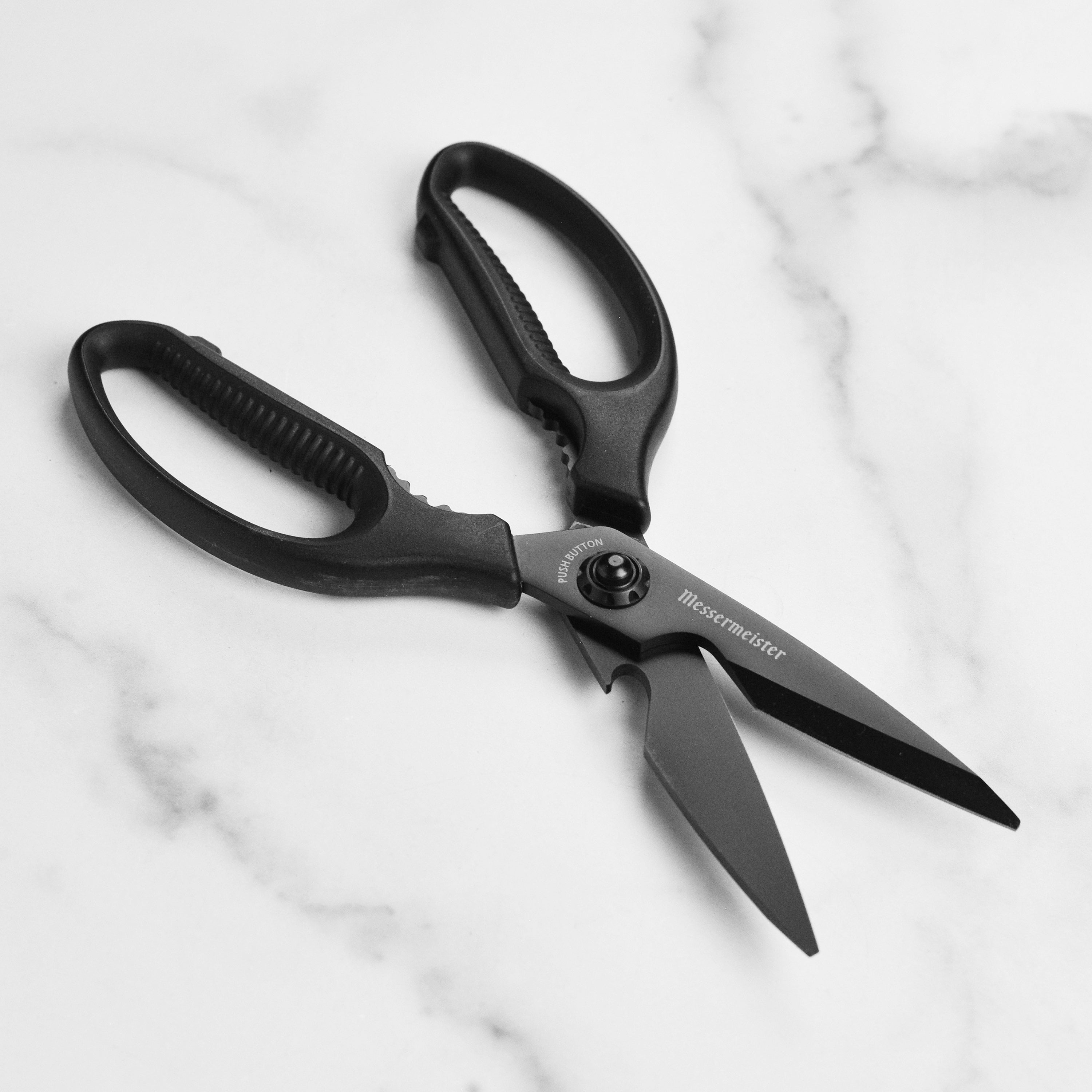 Close-up of titanium shears showing soft-grip handle and push-button blade release