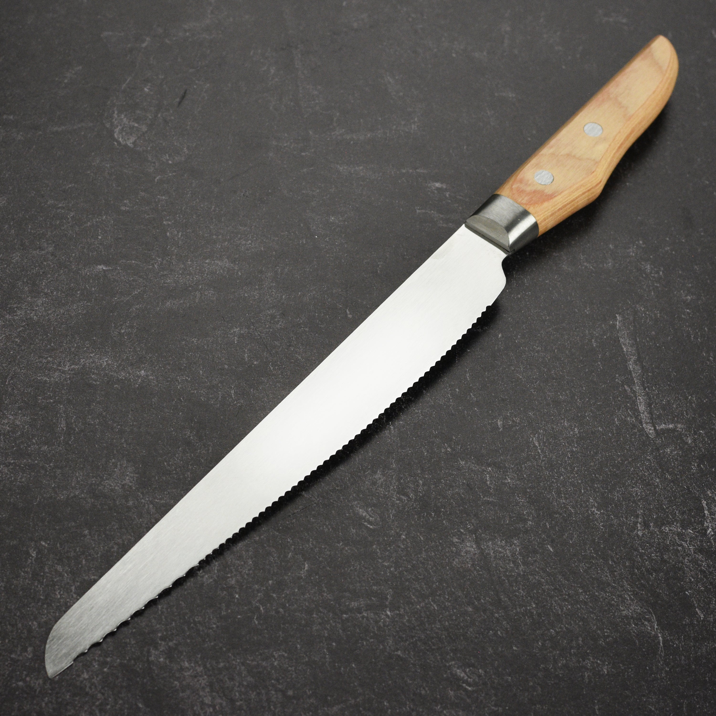 Suncraft Seseragi bread knife displayed on a wooden cutting board with fresh tomatoes.