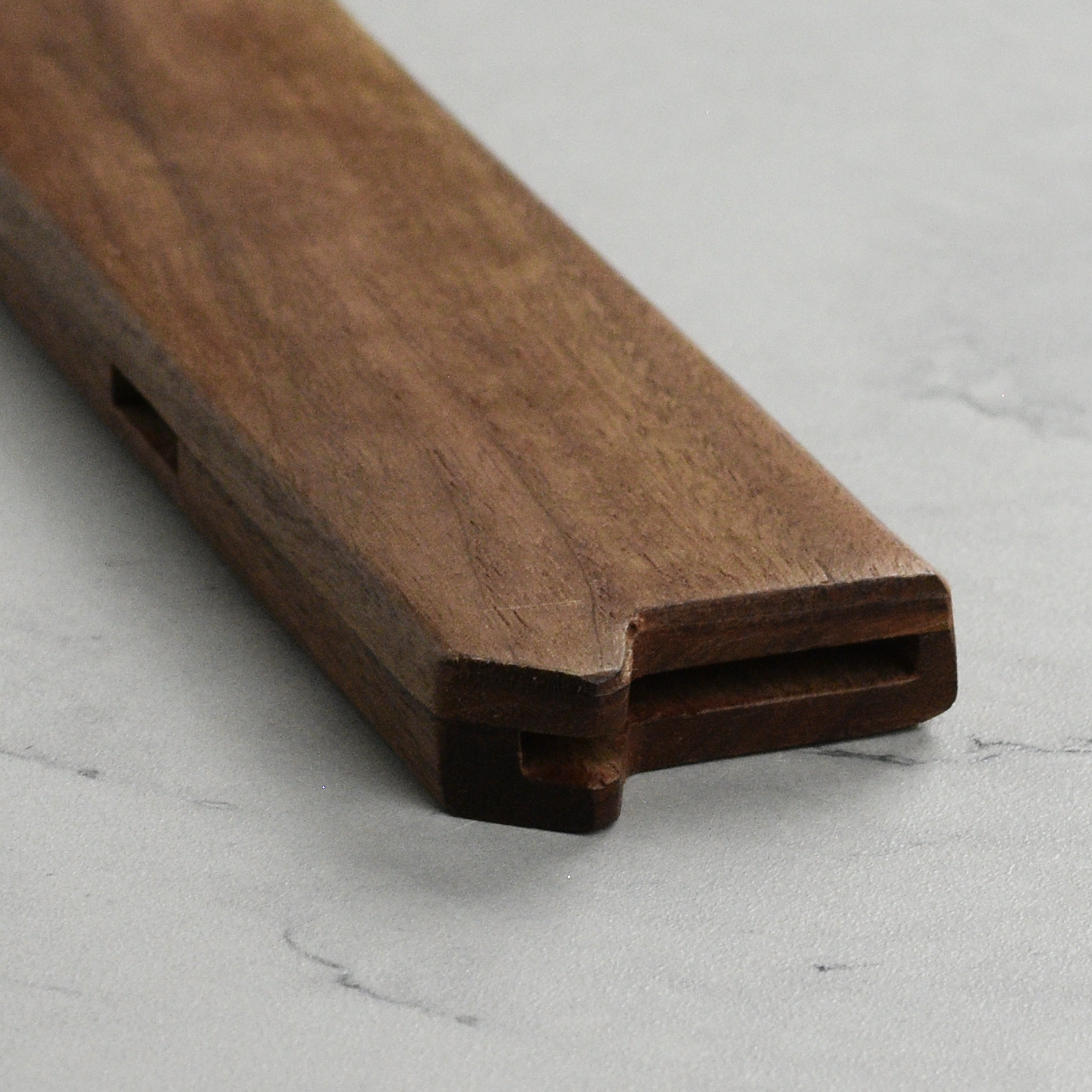 Side view of the walnut knife sheath revealing embedded magnets and vent holes.