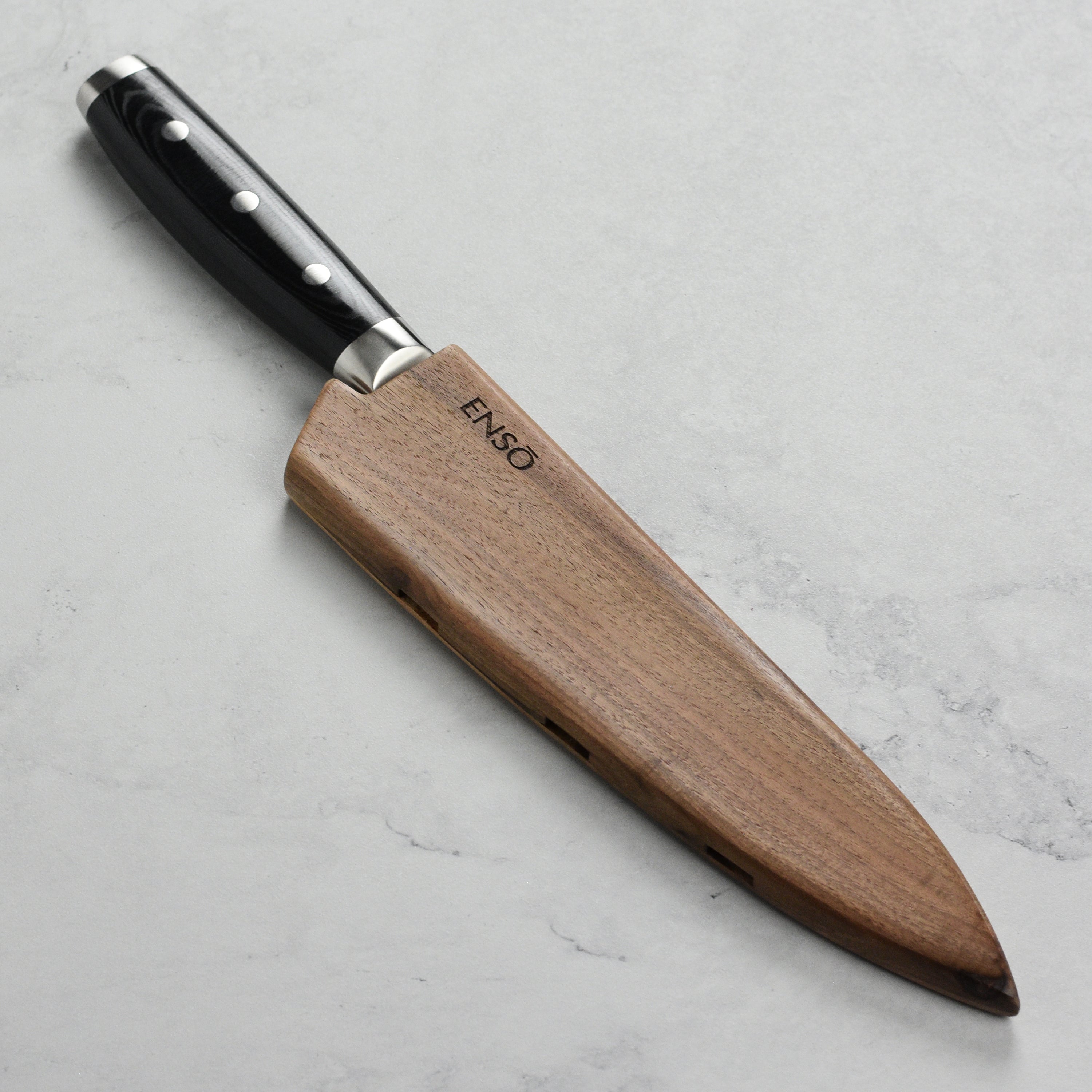Close-up view of Enso magnetic knife sheath demonstrating vent holes and walnut wood texture.