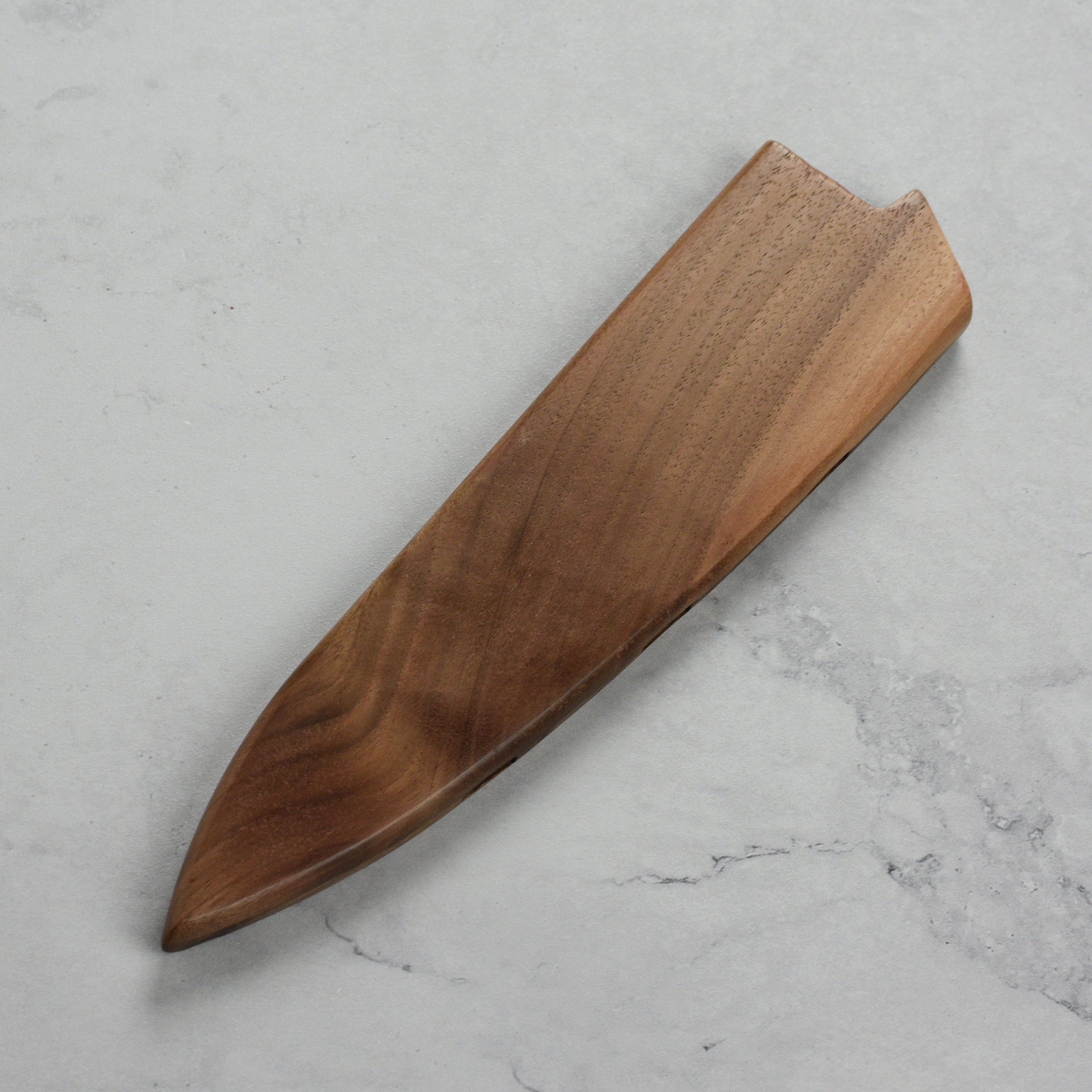 Lifestyle image of chef knife in walnut magnetic sheath, highlighting functionality in a kitchen setting.