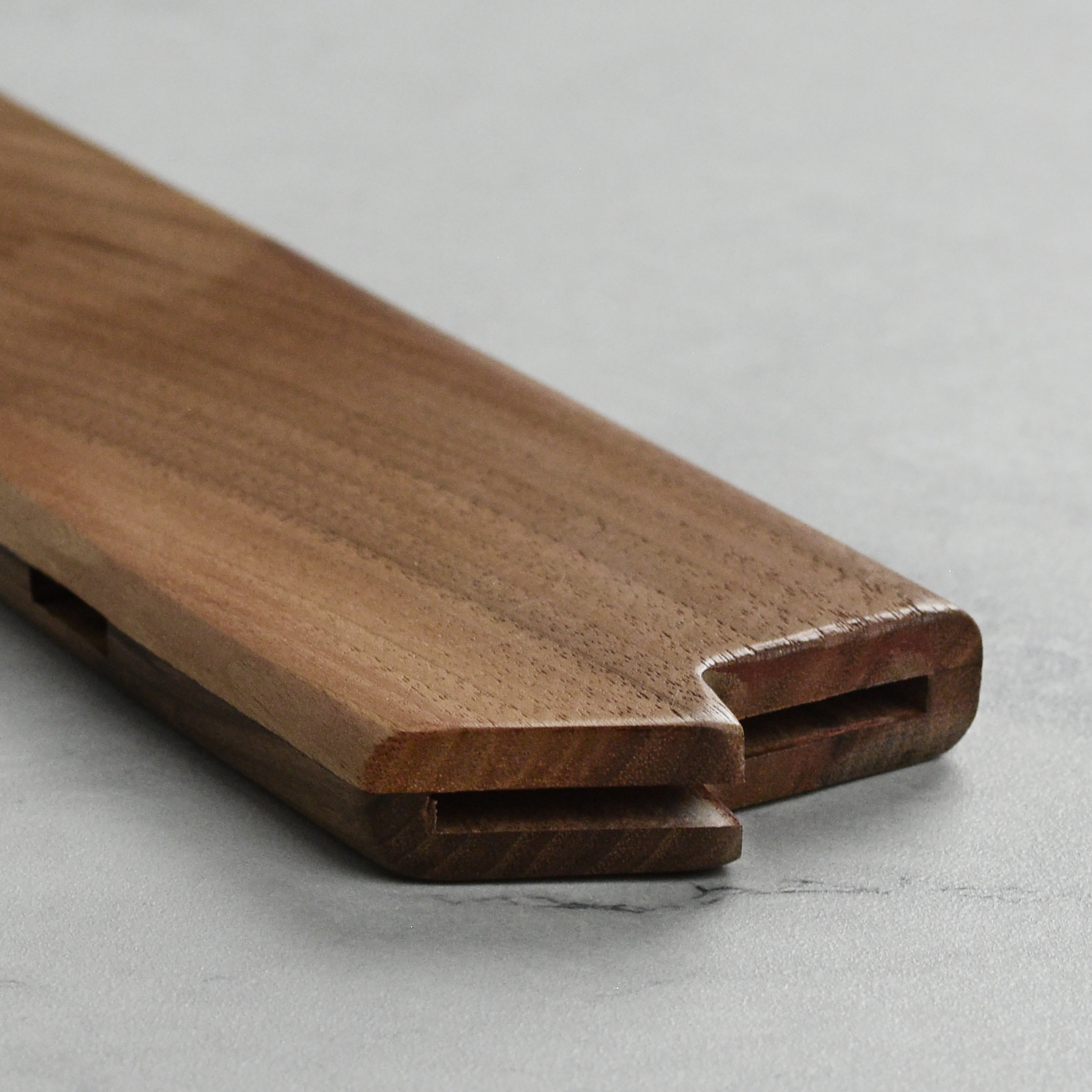 Lifestyle image of chef knife in walnut magnetic sheath, highlighting functionality in a kitchen setting.