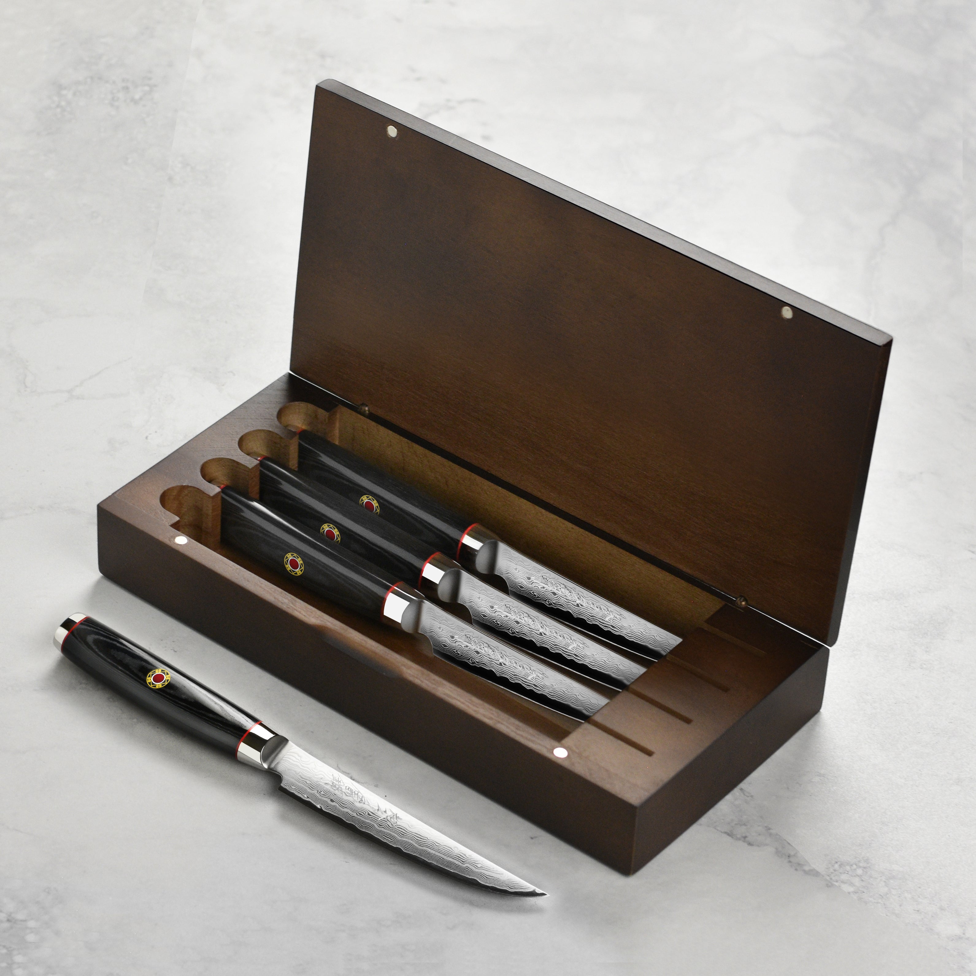 Close-up of Damascus steak knives with engraved blades and black micarta handles