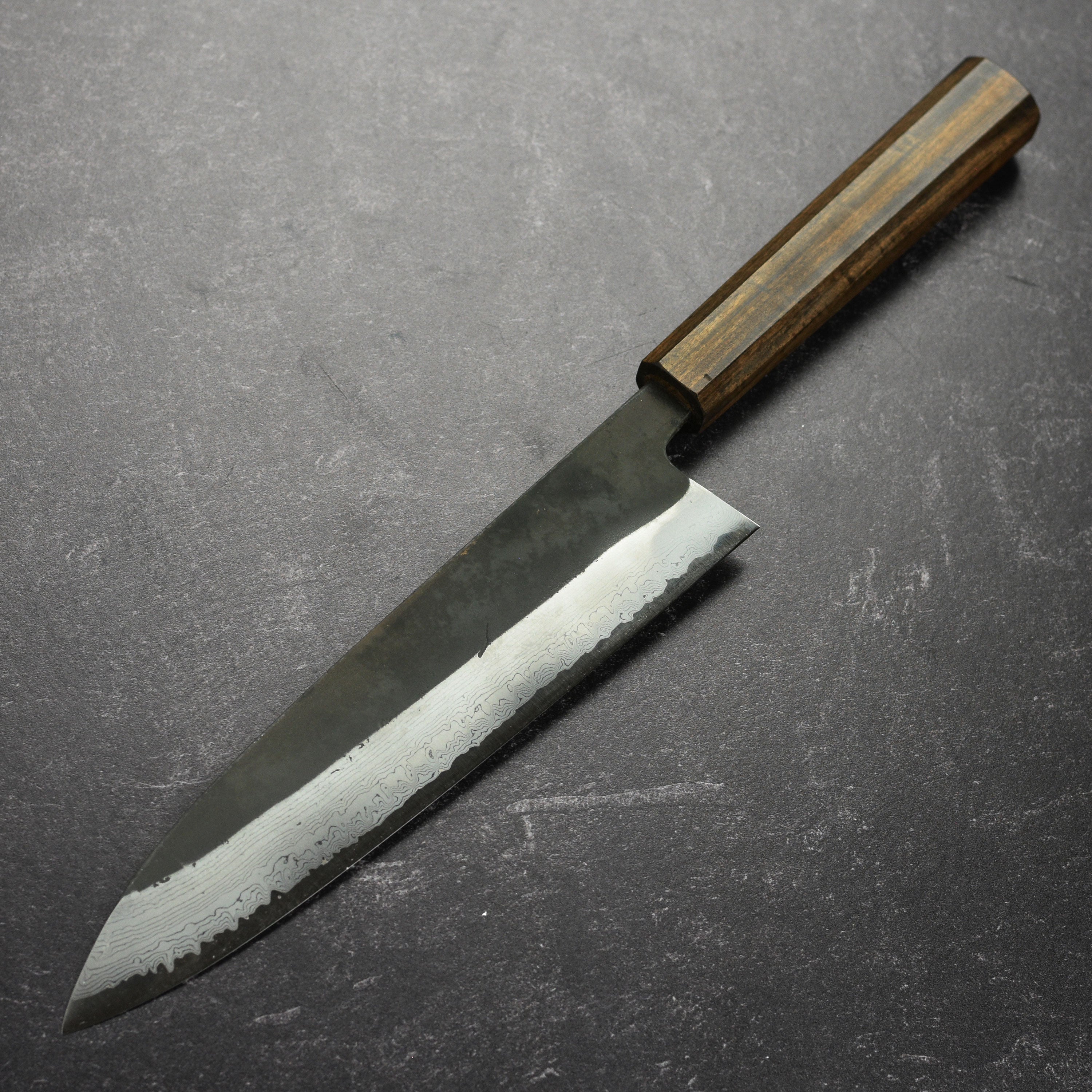 Close-up of the Damascus steel blade, highlighting kurouchi finish and craftsmanship